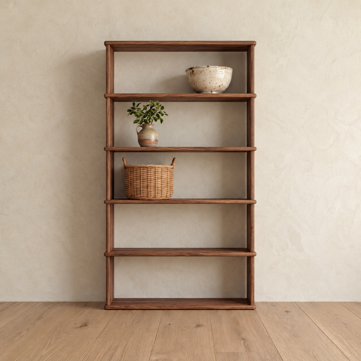 The 5 shelf bookcase in walnut against a plaster wall, with a ceramic bowl, a small potted plant and a woven basket on its upper shelves.