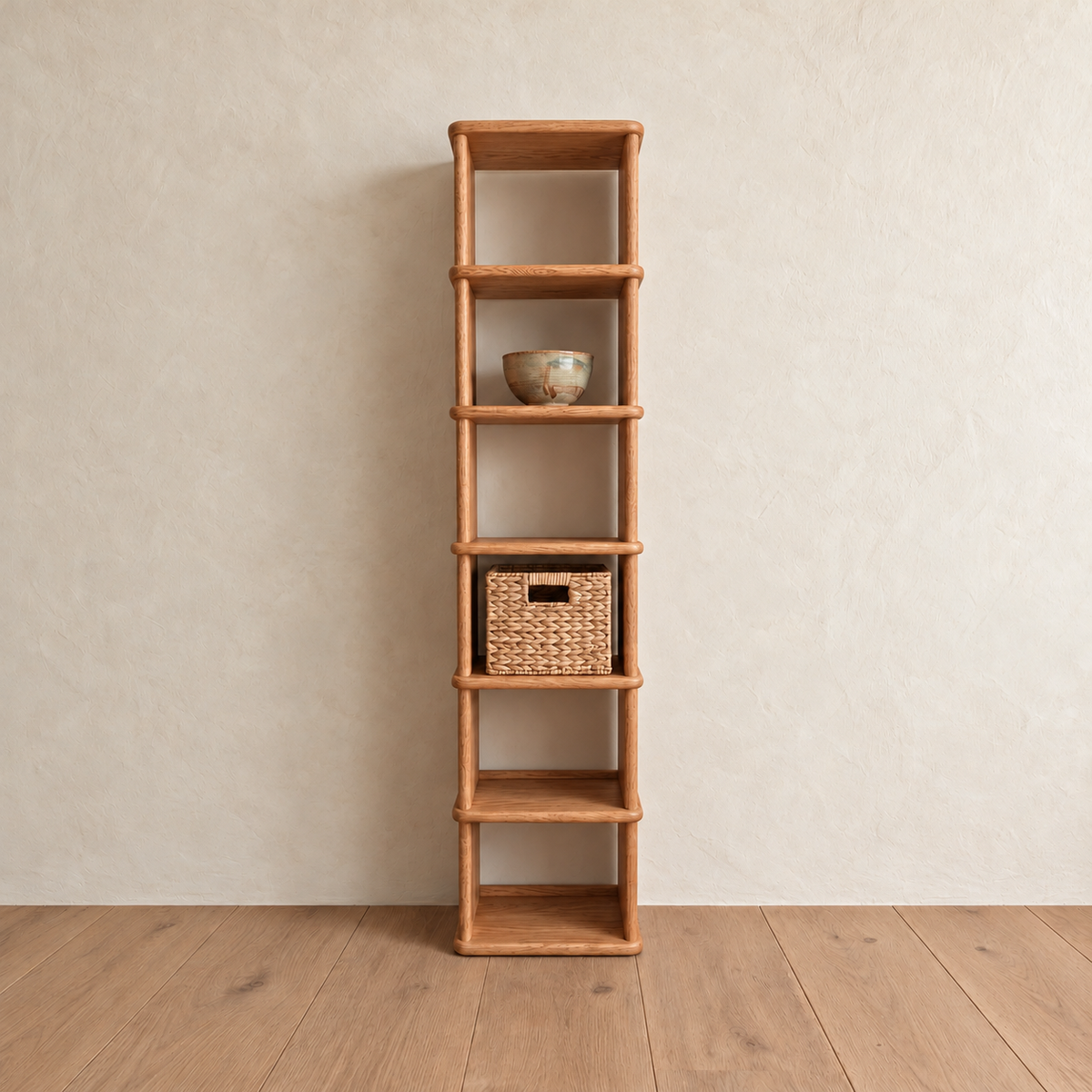 The tall narrow bookcase in red oak against a plaster wall, with a ceramic bowl and a woven basket on its shelves.