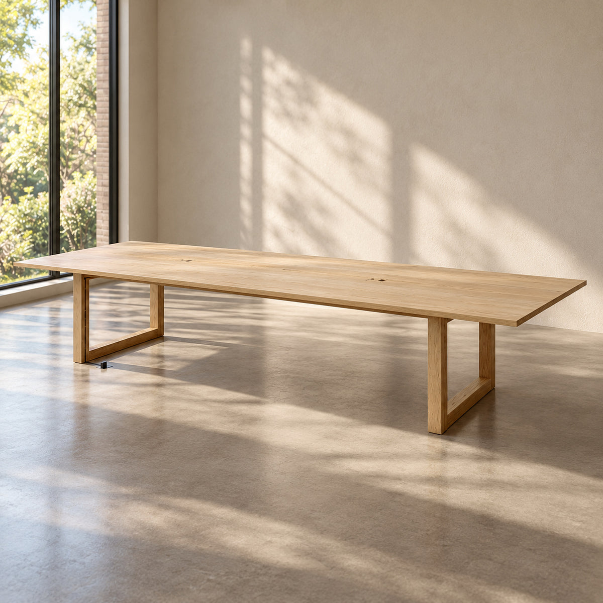 The 10 person conference table in white oak in an empty meeting room, with its long solid top on two rectangular leg frames.