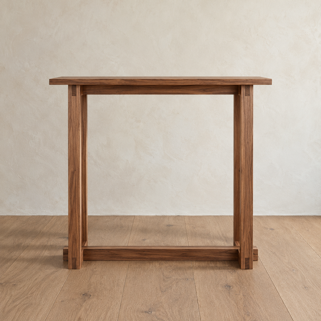 Front view of the 2 person bar table in walnut against a plaster wall, showing the stretcher under the top and the one near the floor.