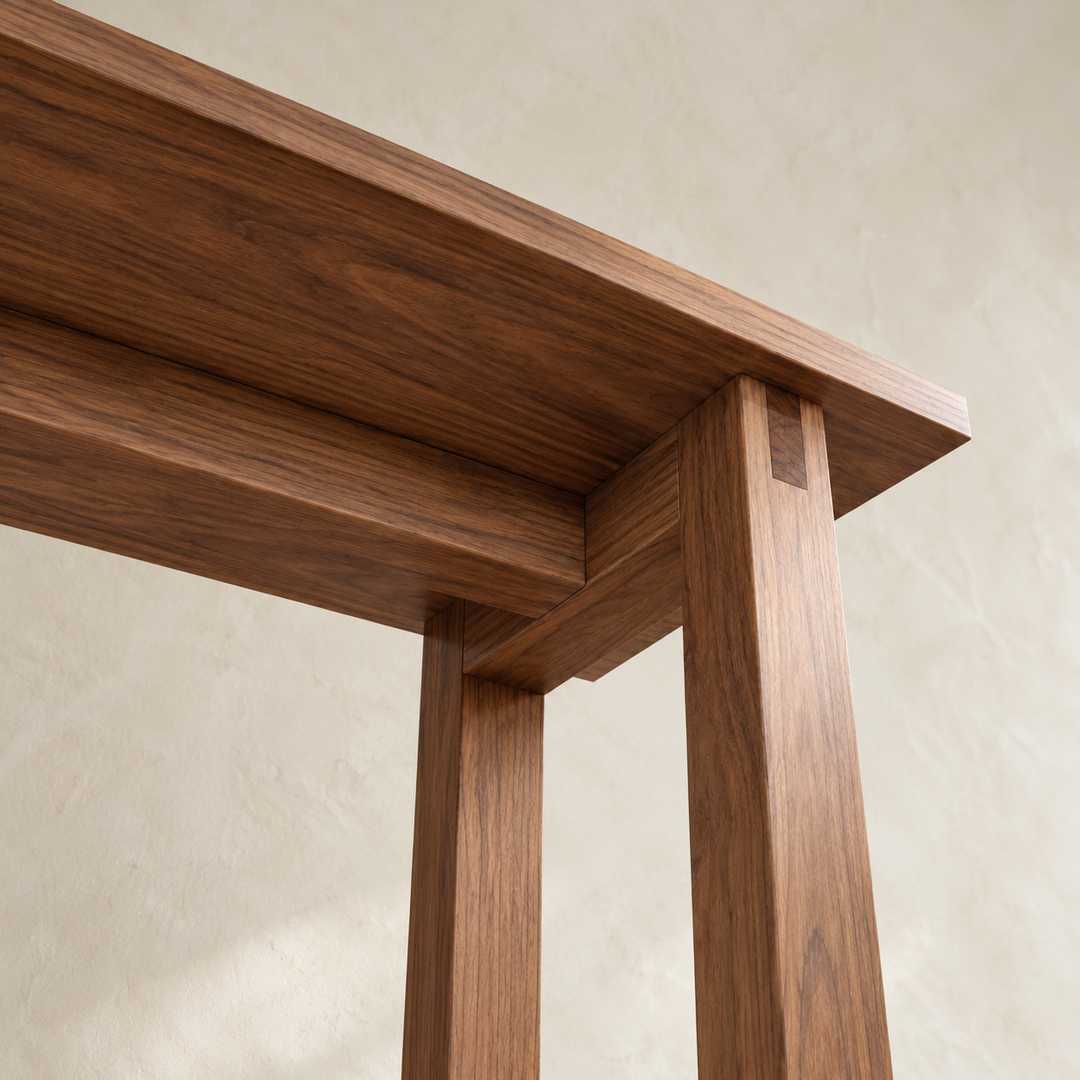 Close-up from below of a corner of the 2 person bar table in walnut, showing the bridle joint at the top of a leg and the rails under the top.