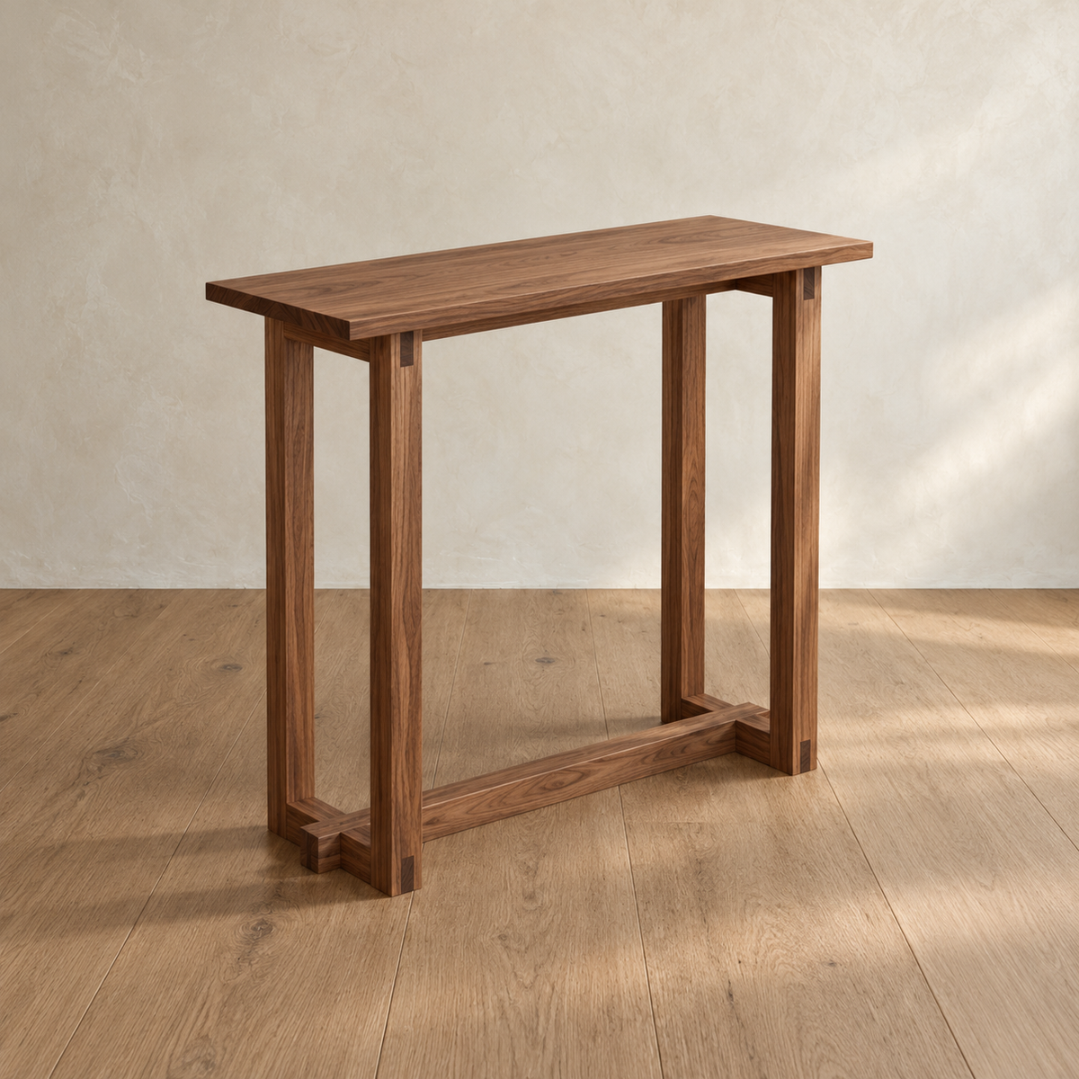 The 2 person bar table in walnut from an angle, with its solid top, bridle-jointed leg frames and a long stretcher near the floor.