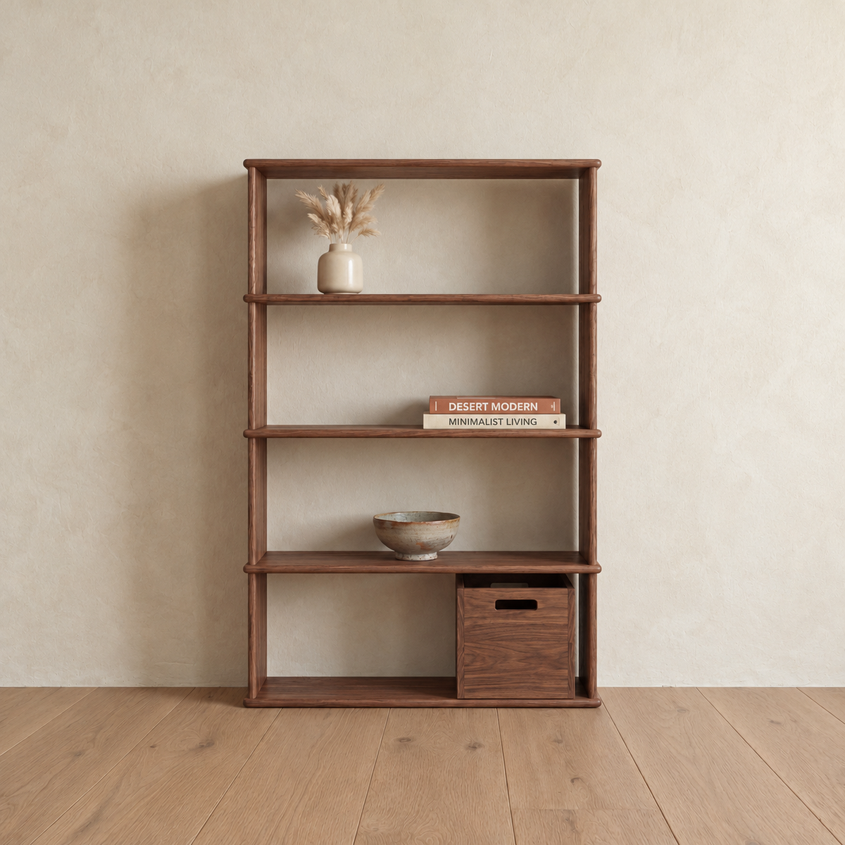 The 4 shelf bookcase in walnut against a plaster wall, holding a small vase of dried grass, two stacked books, a ceramic bowl and a wooden storage cube.