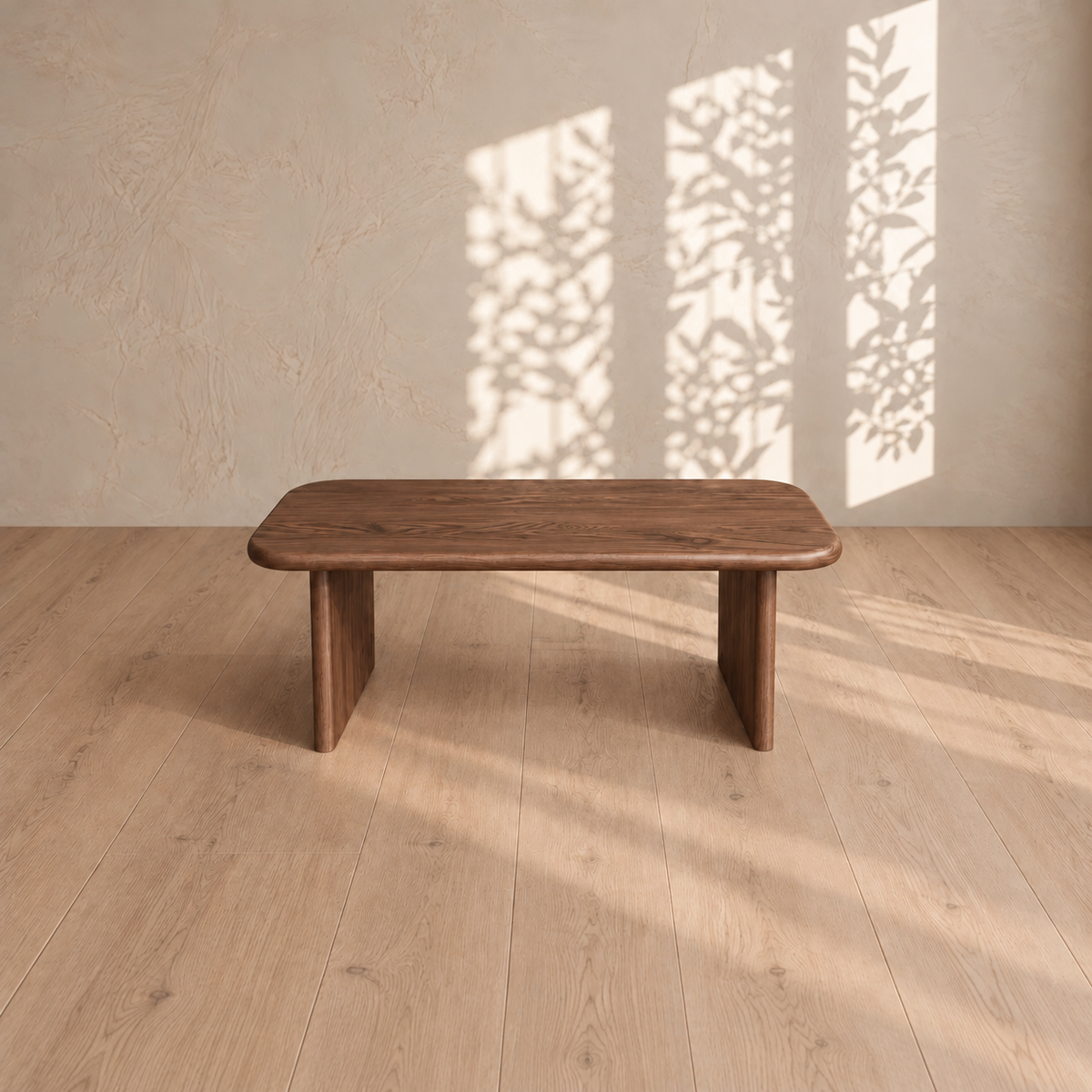 A 40 inch coffee table in walnut on a light wood floor, with leafy window shadows on the plaster wall behind it.