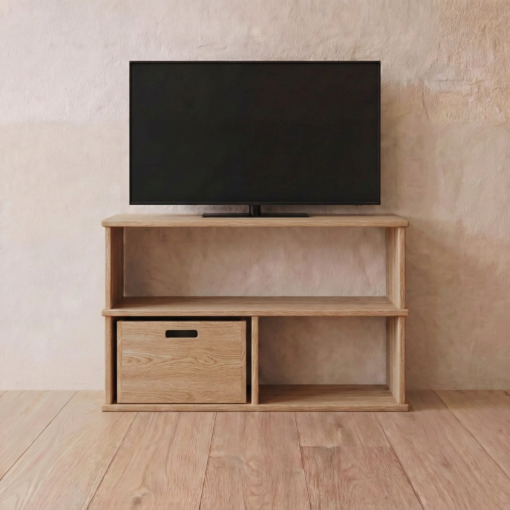 A flat-screen TV is on a 40 inch bookshelf TV stand in white oak with open shelves and a storage box, set against a beige wall on a wooden floor.