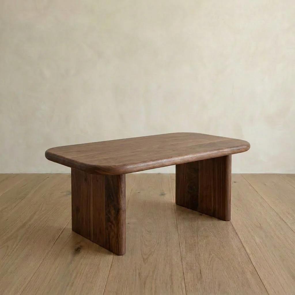 A 40 inch coffee table in walnut with a minimalist design, rounded edges, and two wide flat legs, sits on a light wood floor against a plain beige wall.
