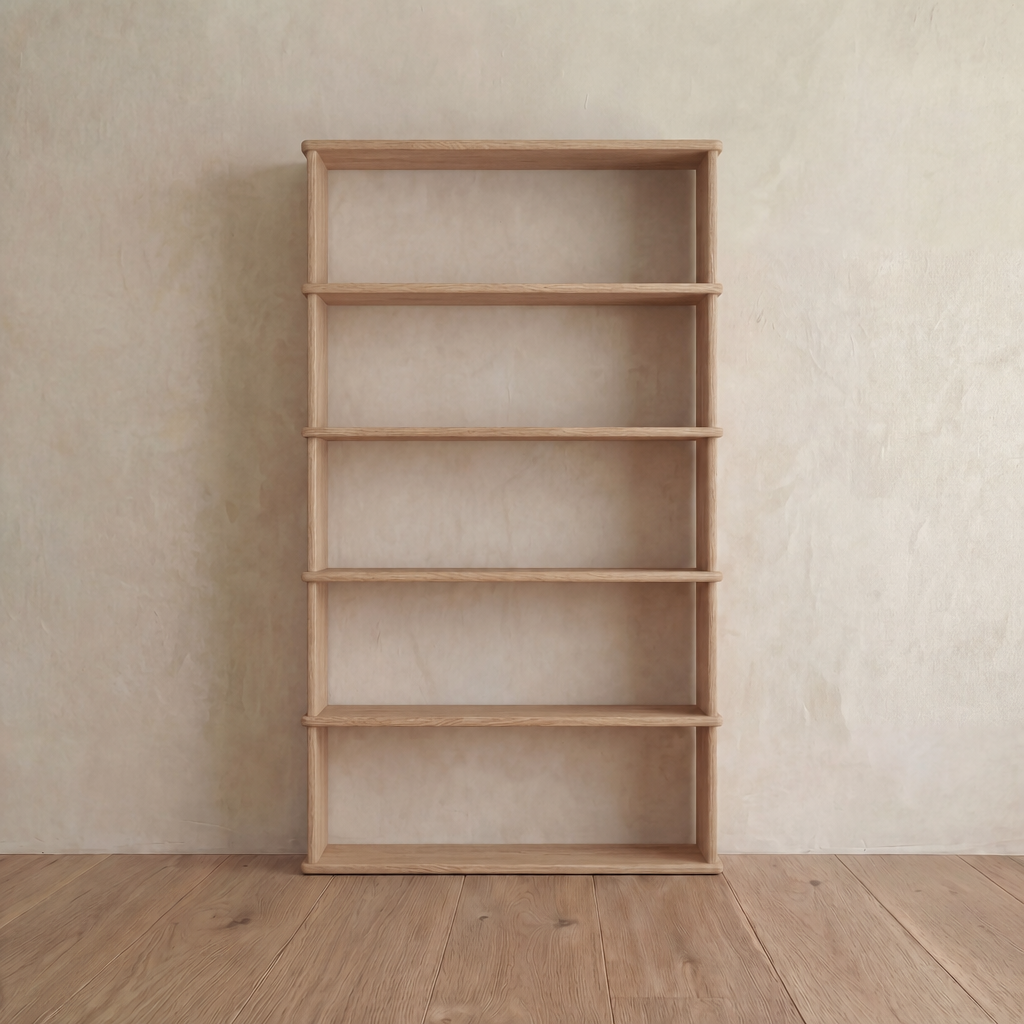 A minimalist 5 shelf bookcase in white oak stands empty against a plain beige wall on a wooden floor.