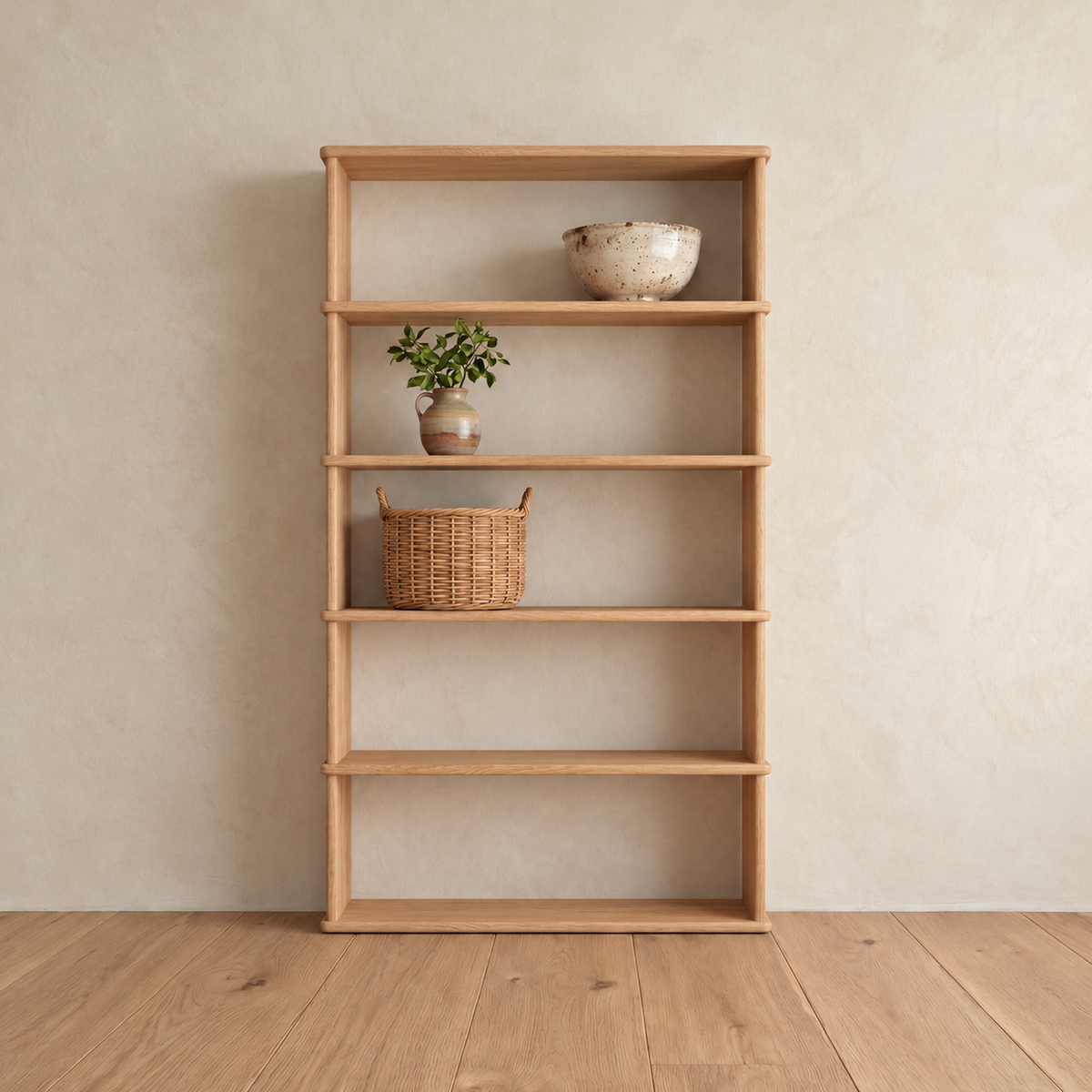 The 5 shelf bookcase in white oak against a plaster wall, with a ceramic bowl, a small potted plant and a woven basket on its upper shelves.