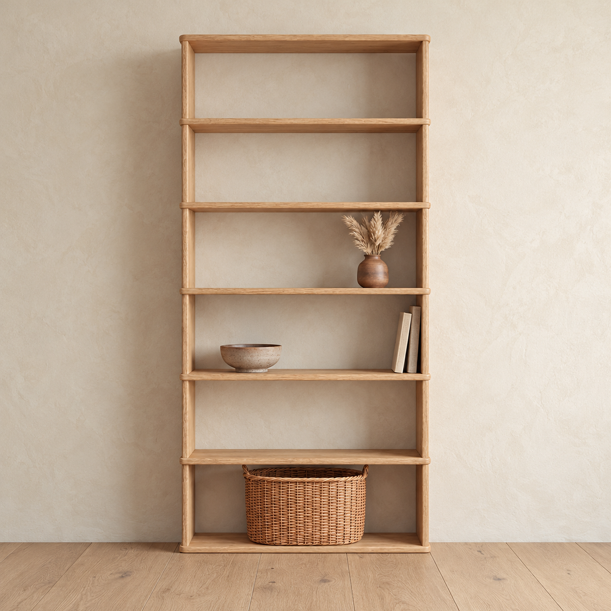 The 6 shelf bookcase in white oak against a plaster wall, with a vase of dried grass, a bowl, a few books and a woven basket on the bottom shelf.