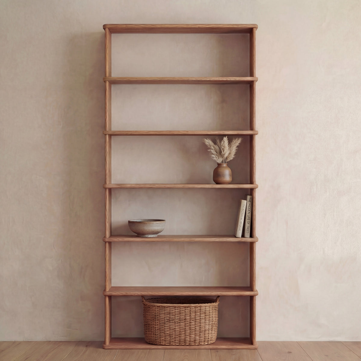 A minimal, tidy setting features a 6 shelf bookcase in red oak against a beige wall, displaying a brown bowl, a vase with dried grass, several books, and a wicker basket on the bottom shelf.