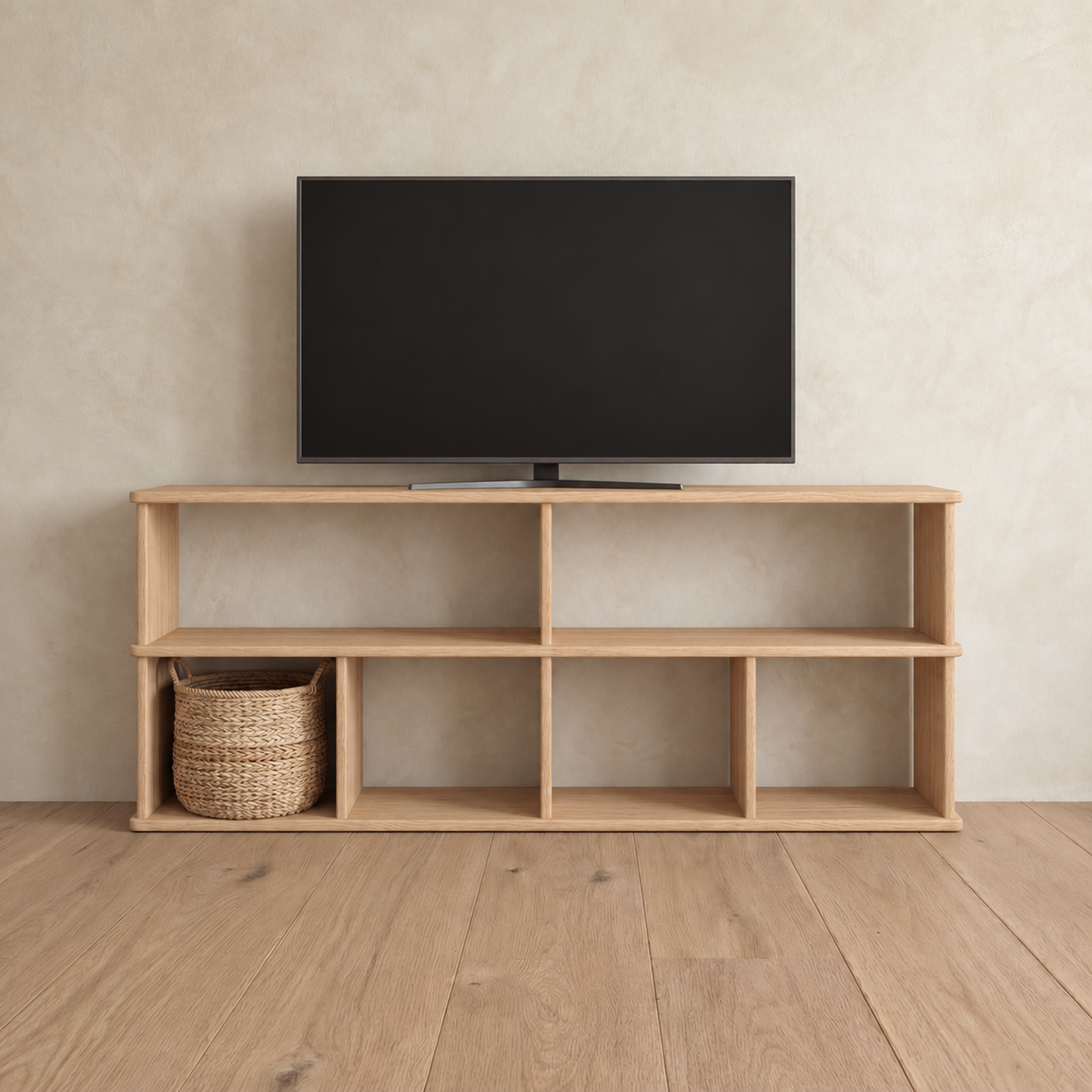 The 65 inch bookshelf TV stand in white oak holding a flat-screen TV, with a woven basket in one of the lower compartments.