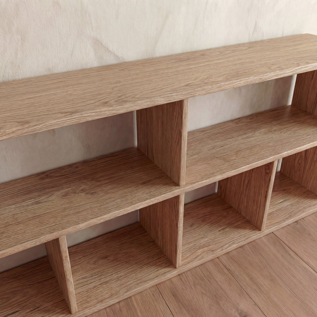 The 65 inch bookshelf TV stand in white oak features six open rectangular compartments and a natural wood grain finish, set against a light-colored wall on a wooden floor.