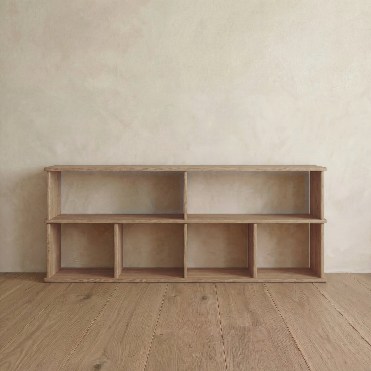 The 65 inch bookshelf TV stand in white oak stands on a wooden floor by a light beige textured wall. It features six rectangular compartments, clean lines, and a minimalist design with a natural wood finish.