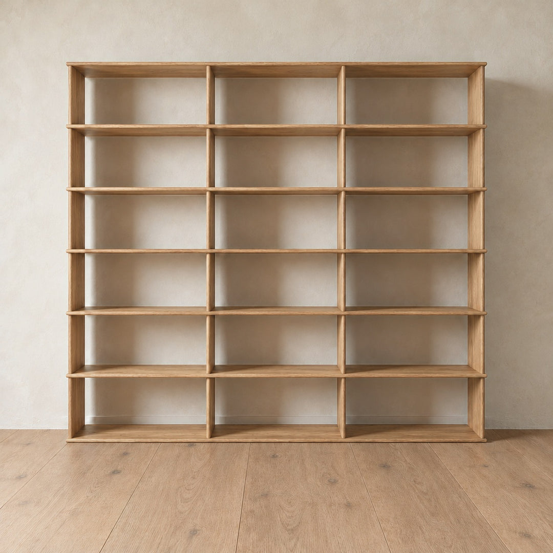 The 7 foot tall bookcase in white oak, 3 columns wide, empty, against a light plaster wall on a light oak floor.