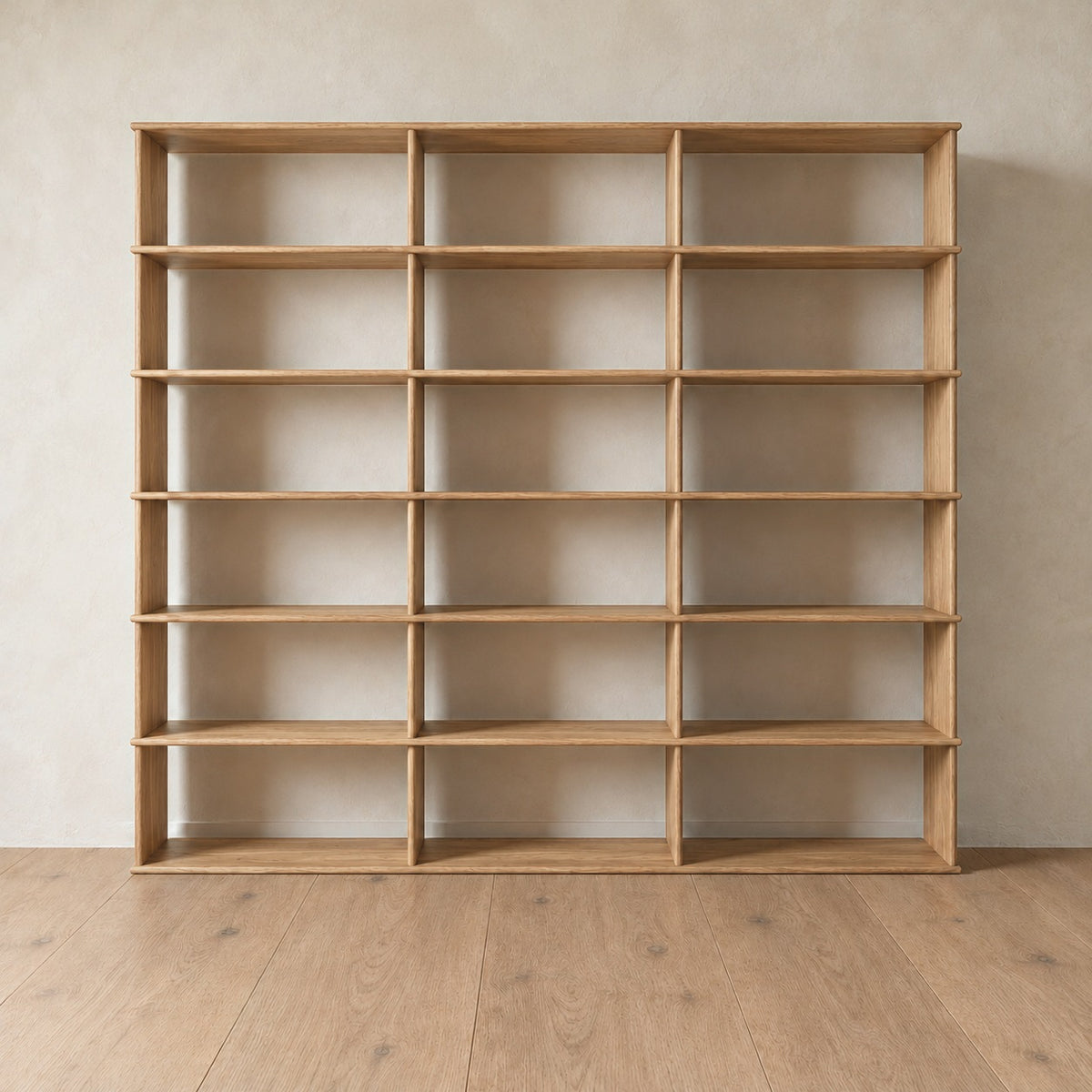 The 7 foot tall bookcase in white oak, 3 columns wide, empty, against a light plaster wall on a light oak floor.