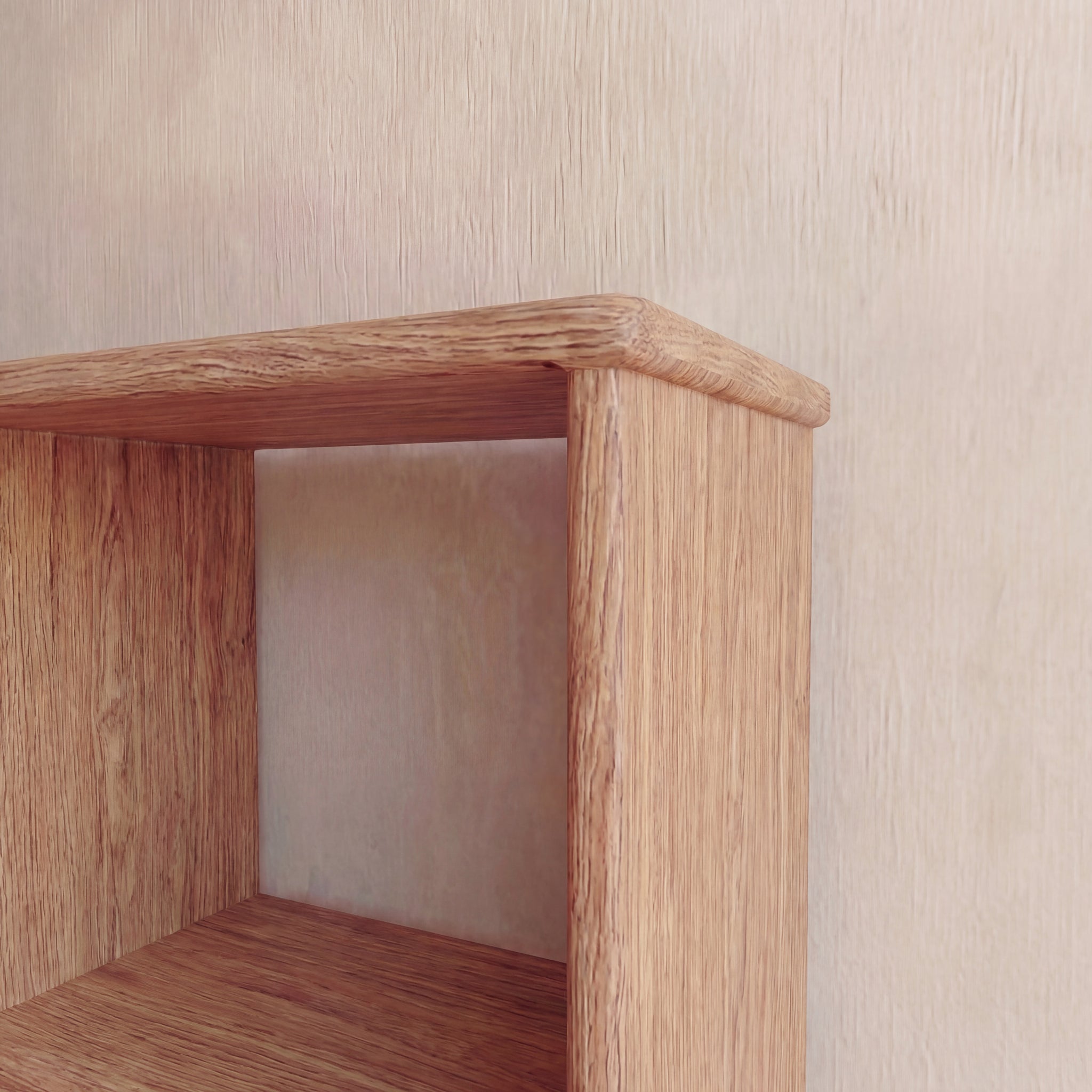 A close-up of the top corner of the Nine cube bookshelf in red oak against a light, textured wall highlights its natural wood grain finish and simple, rectangular design.