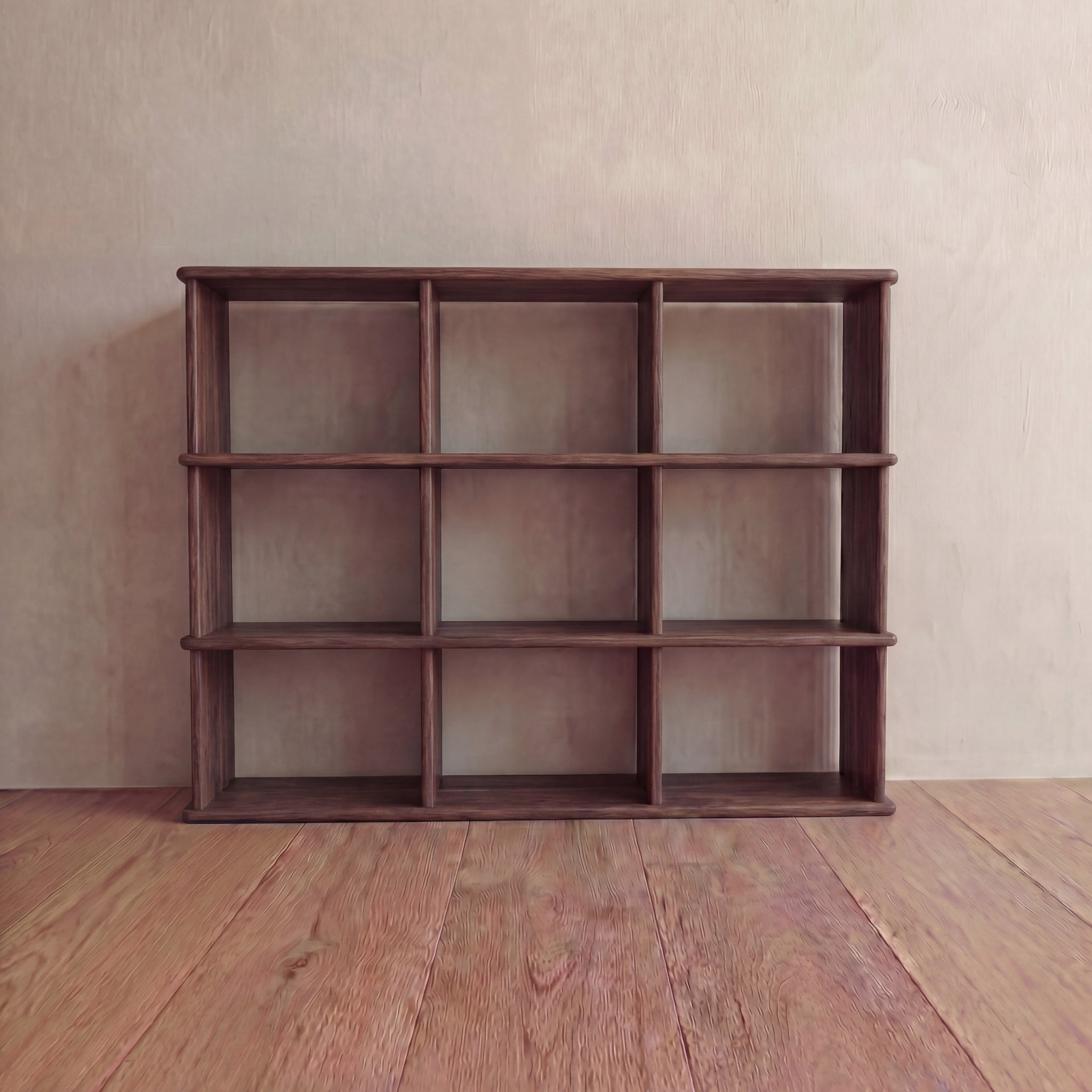 The Nine cube bookshelf in walnut, handmade in Vancouver from solid wood, features nine empty square compartments and stands against a pale wall on a wooden floor.