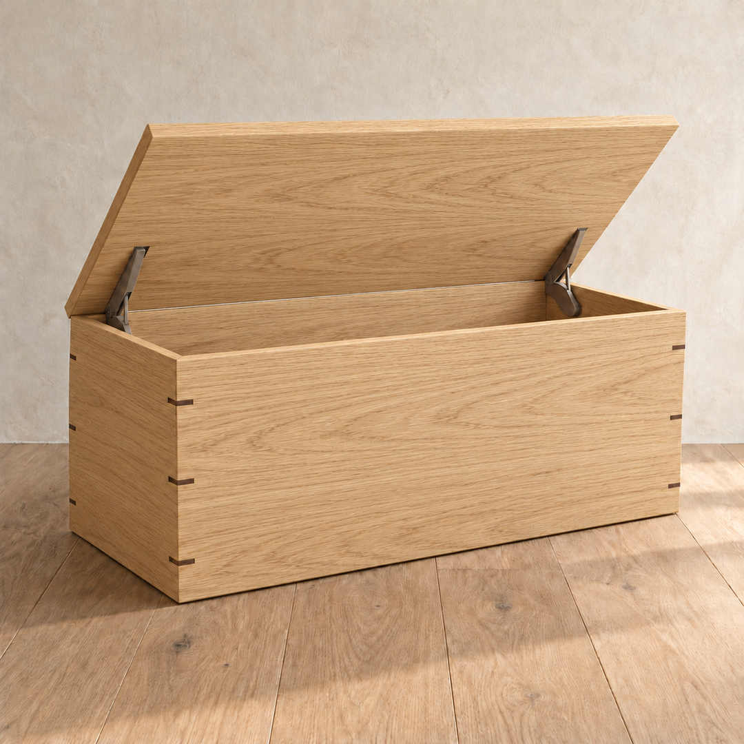 The chest coffee table in white oak with the lid open on two lid stays, showing the empty storage space inside.