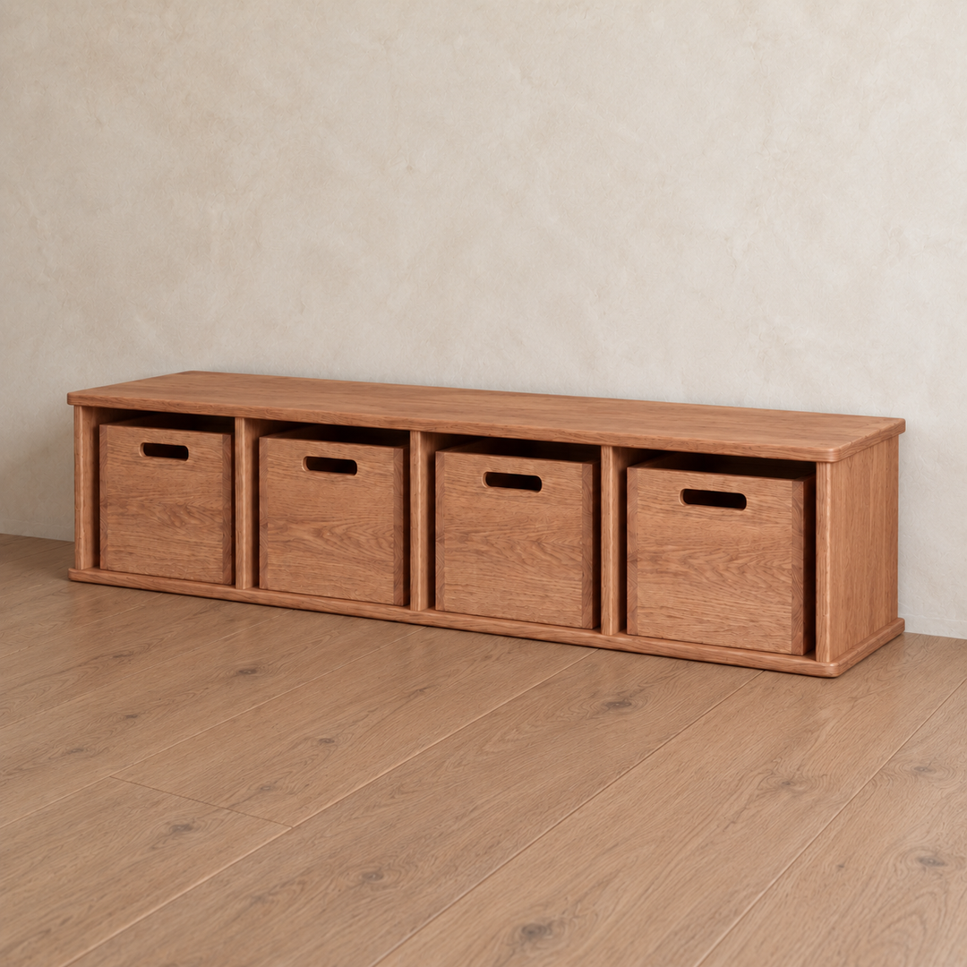 Entryway cubby bench in red oak featuring a low wooden design with four open cubbies, each containing a matching storage bin with a cutout handle.