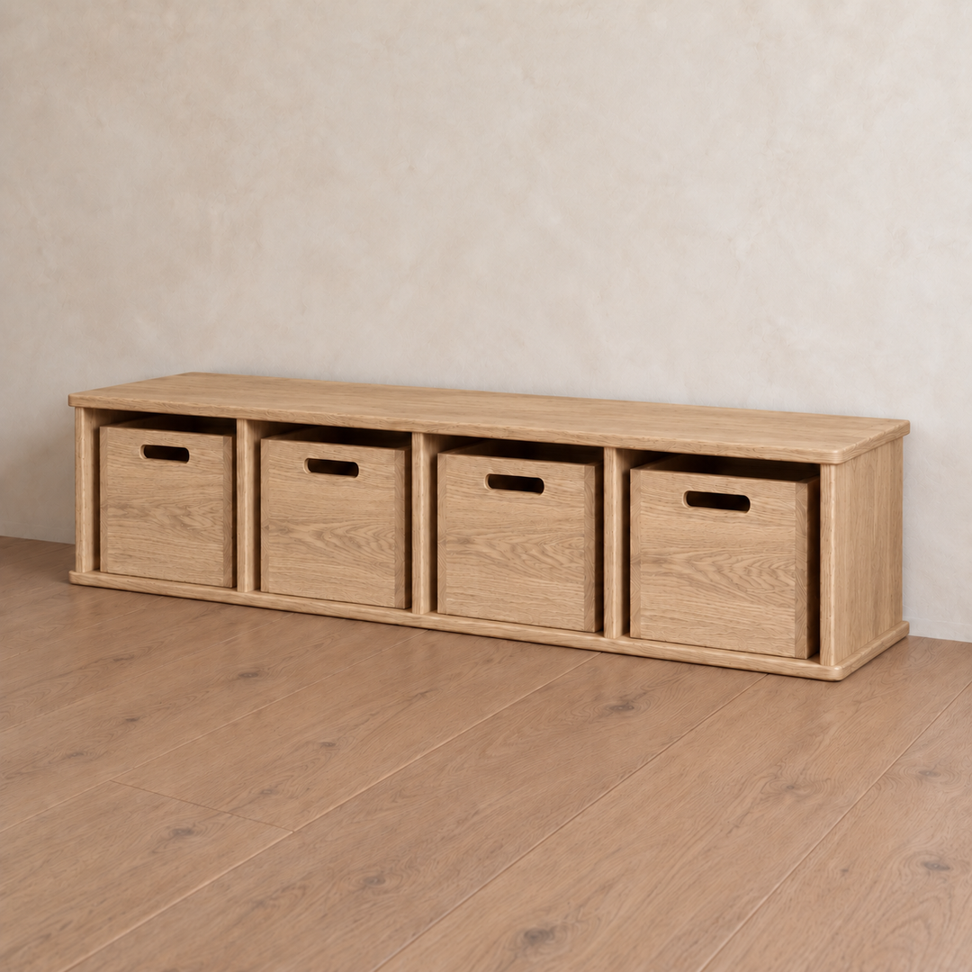 Entryway cubby bench in red oak featuring a low wooden design with four open cubbies, each containing a matching storage bin with a cutout handle.