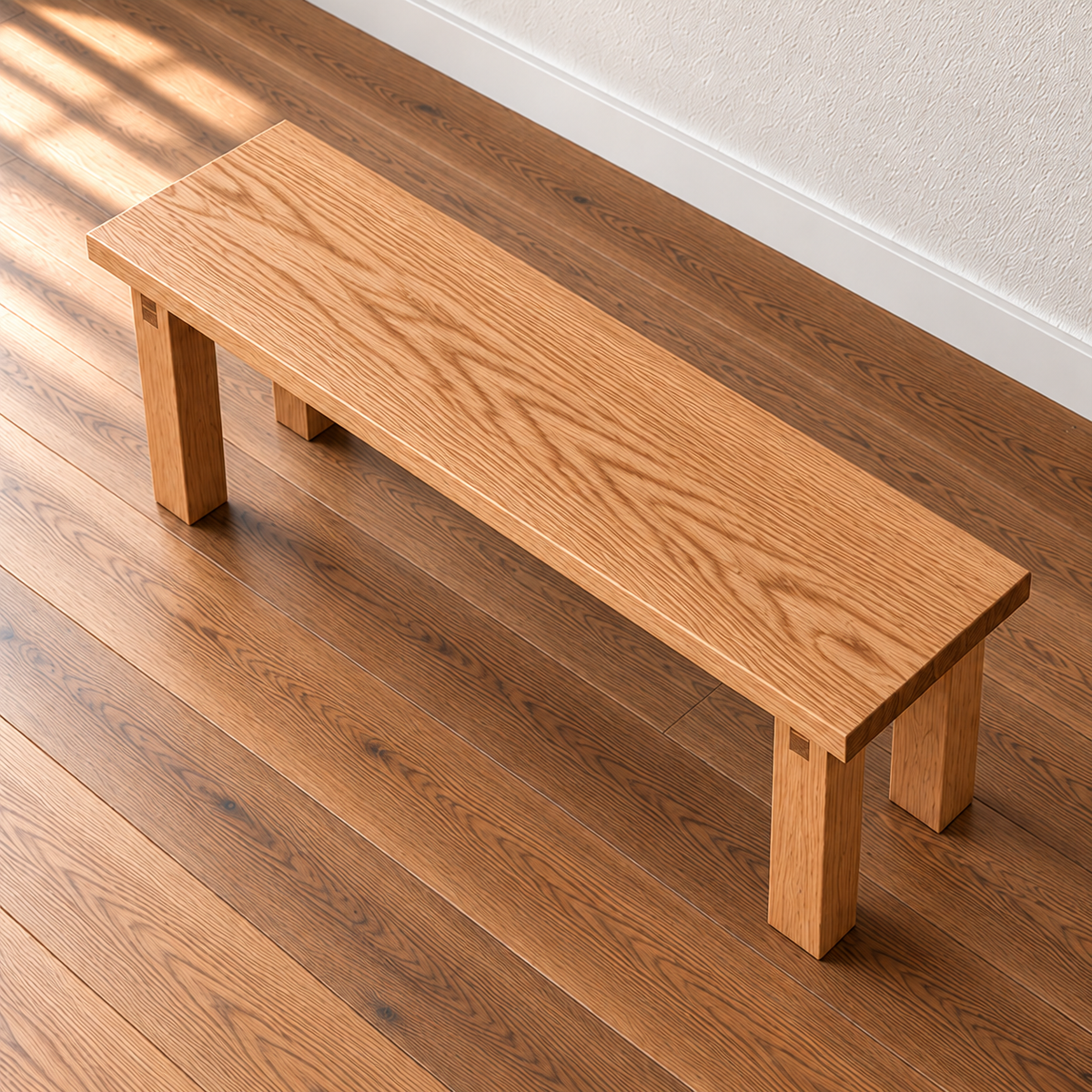 The farmhouse bench in red oak seen from above at an angle, showing the grain running the length of the solid top.