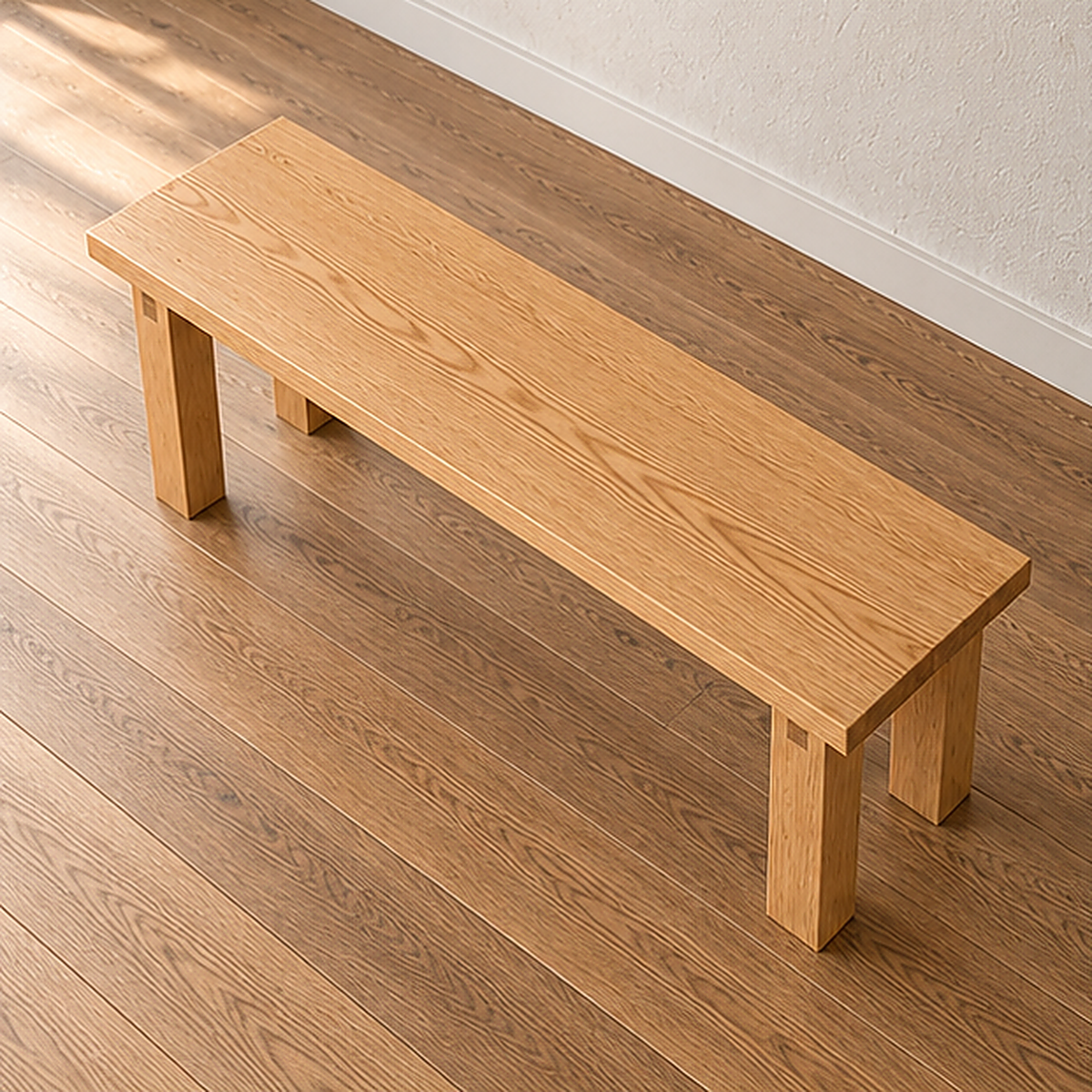 The farmhouse bench in white oak seen from above at an angle, showing the grain running the length of the solid top.