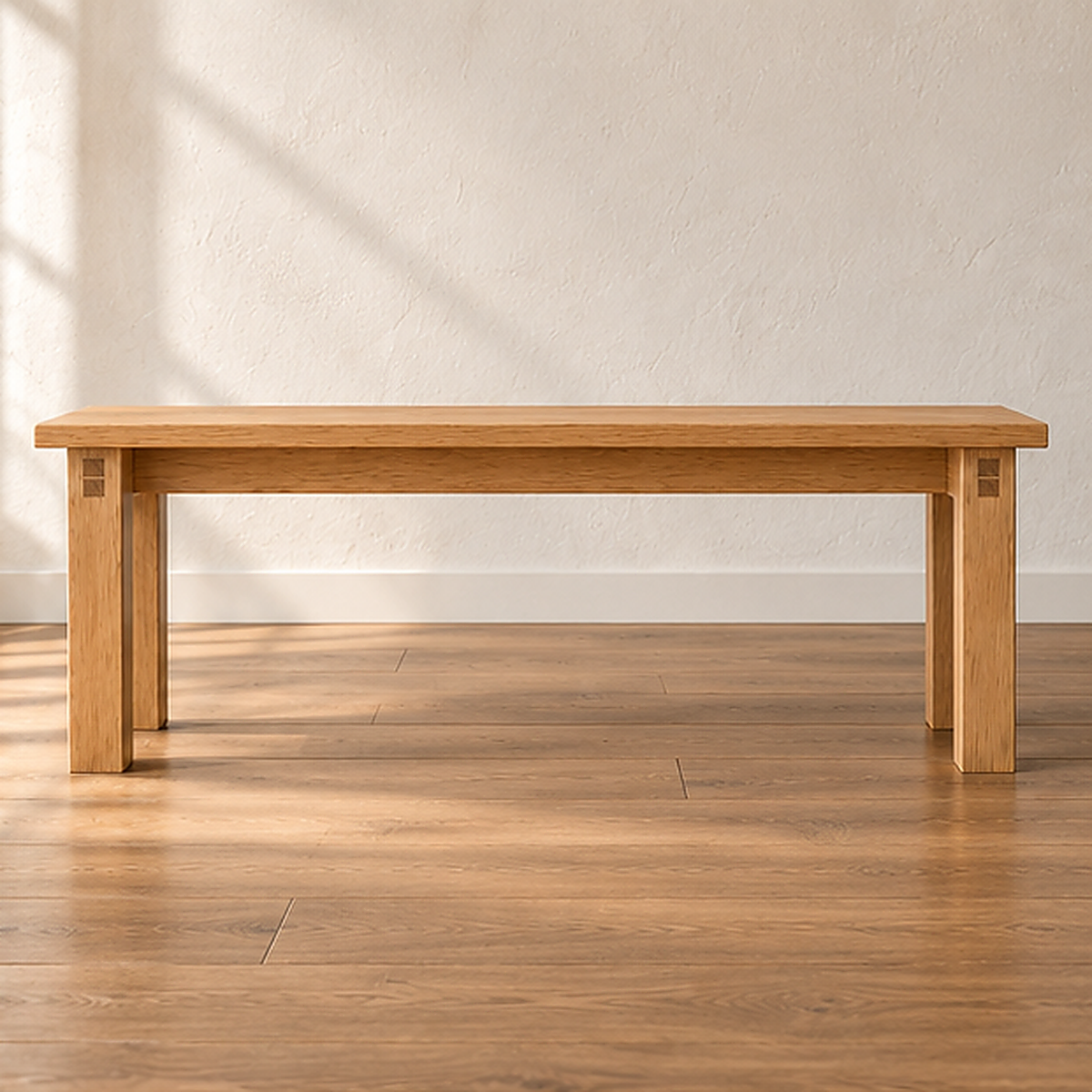 A farmhouse bench in white oak with a thick solid top and four square legs, against a sunlit white wall on a wood floor.