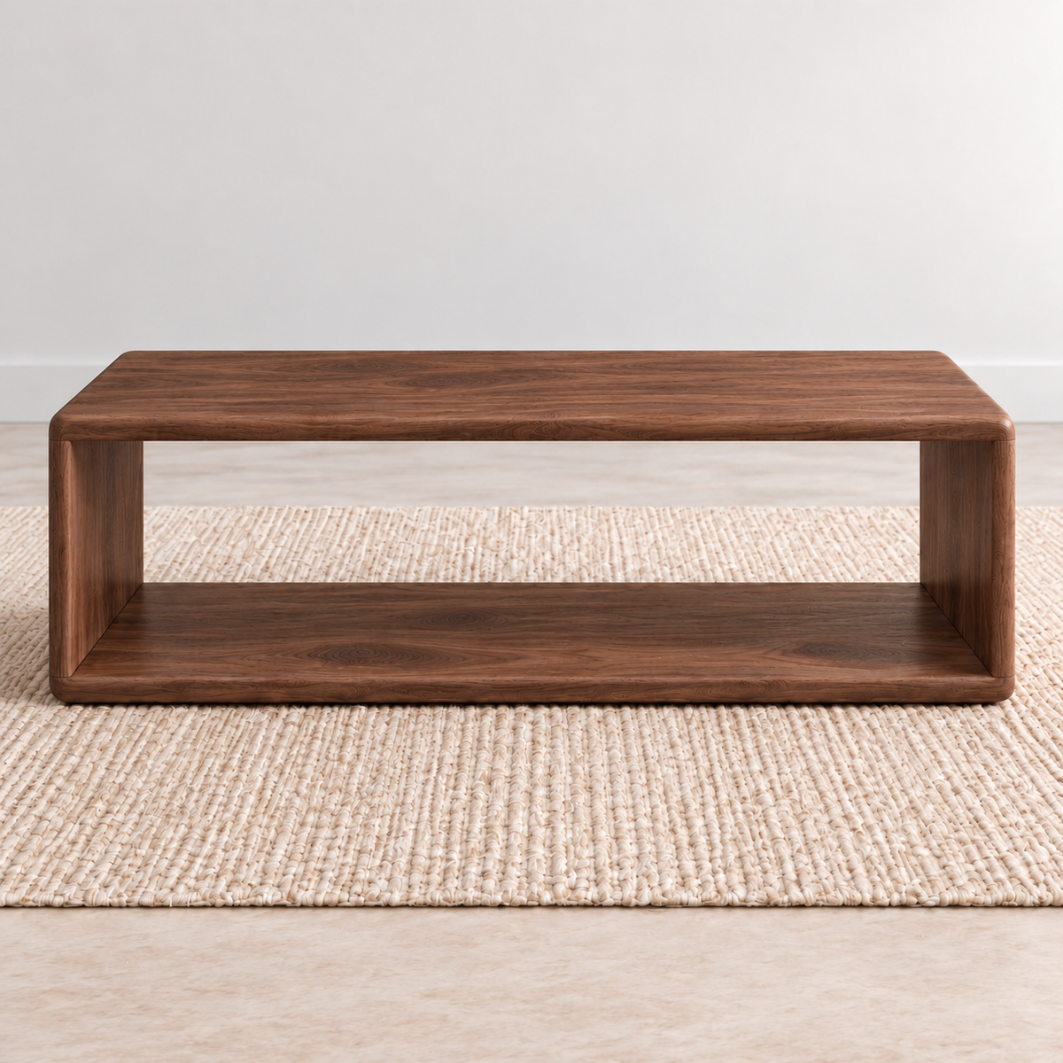 A Japandi coffee table in walnut: a low, open rectangle with softly rounded corners and a lower shelf, on a woven jute rug against a plain light wall.