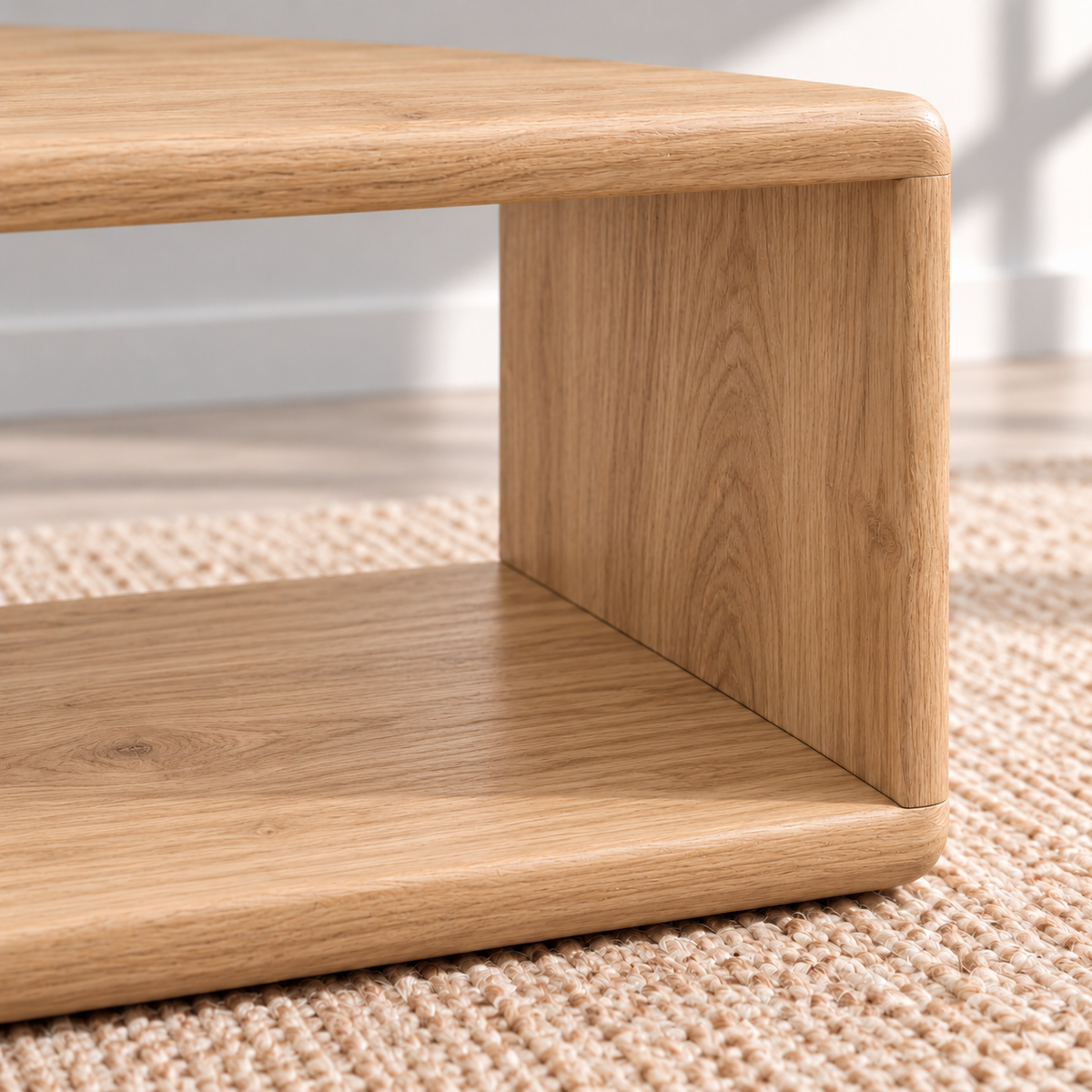 Close-up of a corner of the Japandi coffee table in white oak, where the top curves smoothly down into the side and the grain continues around the corner.