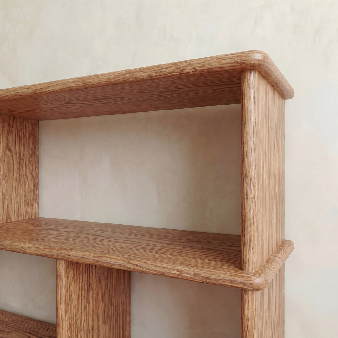 A close-up of the handmade Horizontal bookshelf in red oak, crafted in Vancouver with a natural finish and smooth, rounded edges. Set against a beige wall, the shelves are empty.