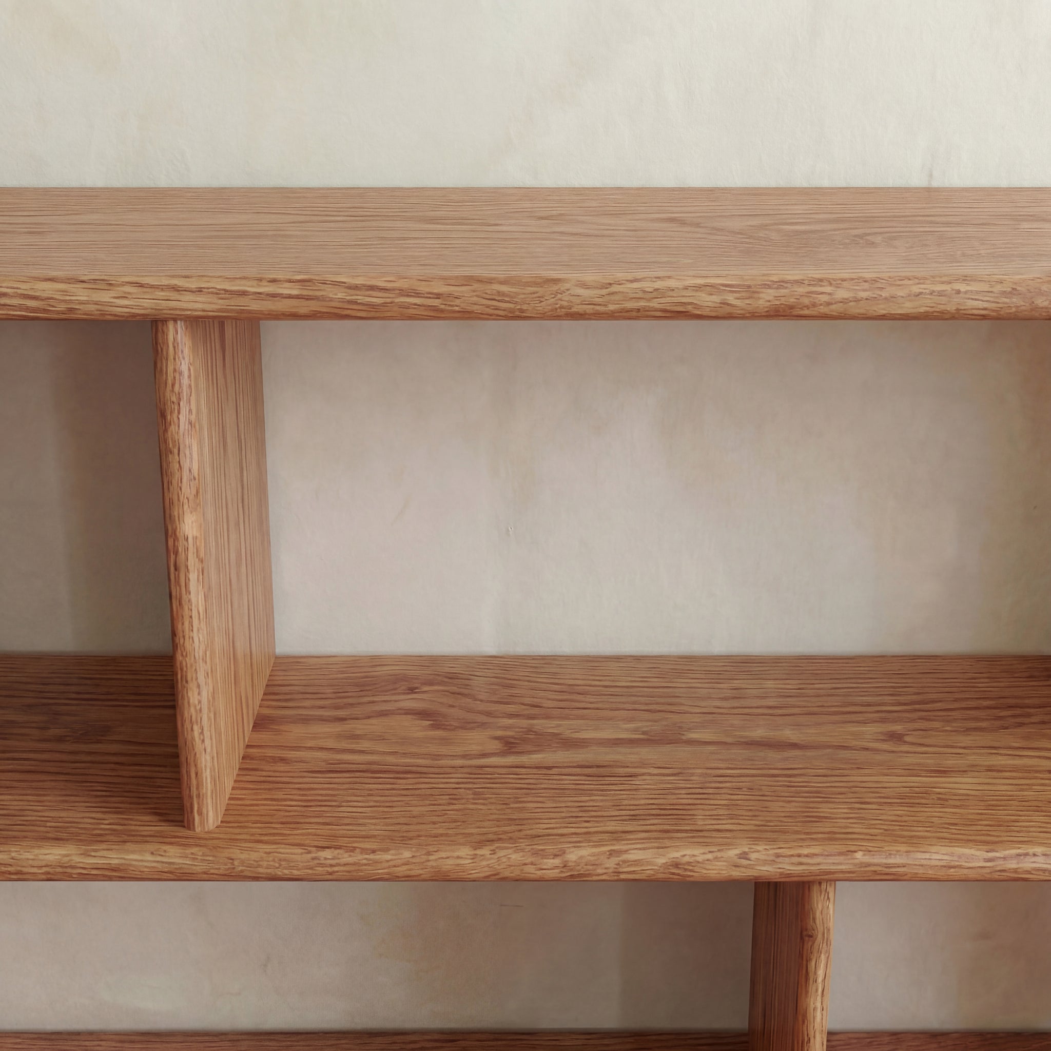 A close-up of the Horizontal bookshelf in red oak, handmade in Vancouver, features empty shelves and vertical dividers with a light wood grain finish against a plain beige wall. The clean, low design highlights its minimalist craftsmanship.