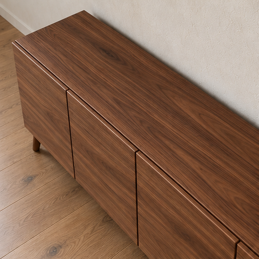 The media console in walnut seen from above, showing the grain across the top and the narrow gaps between the doors.