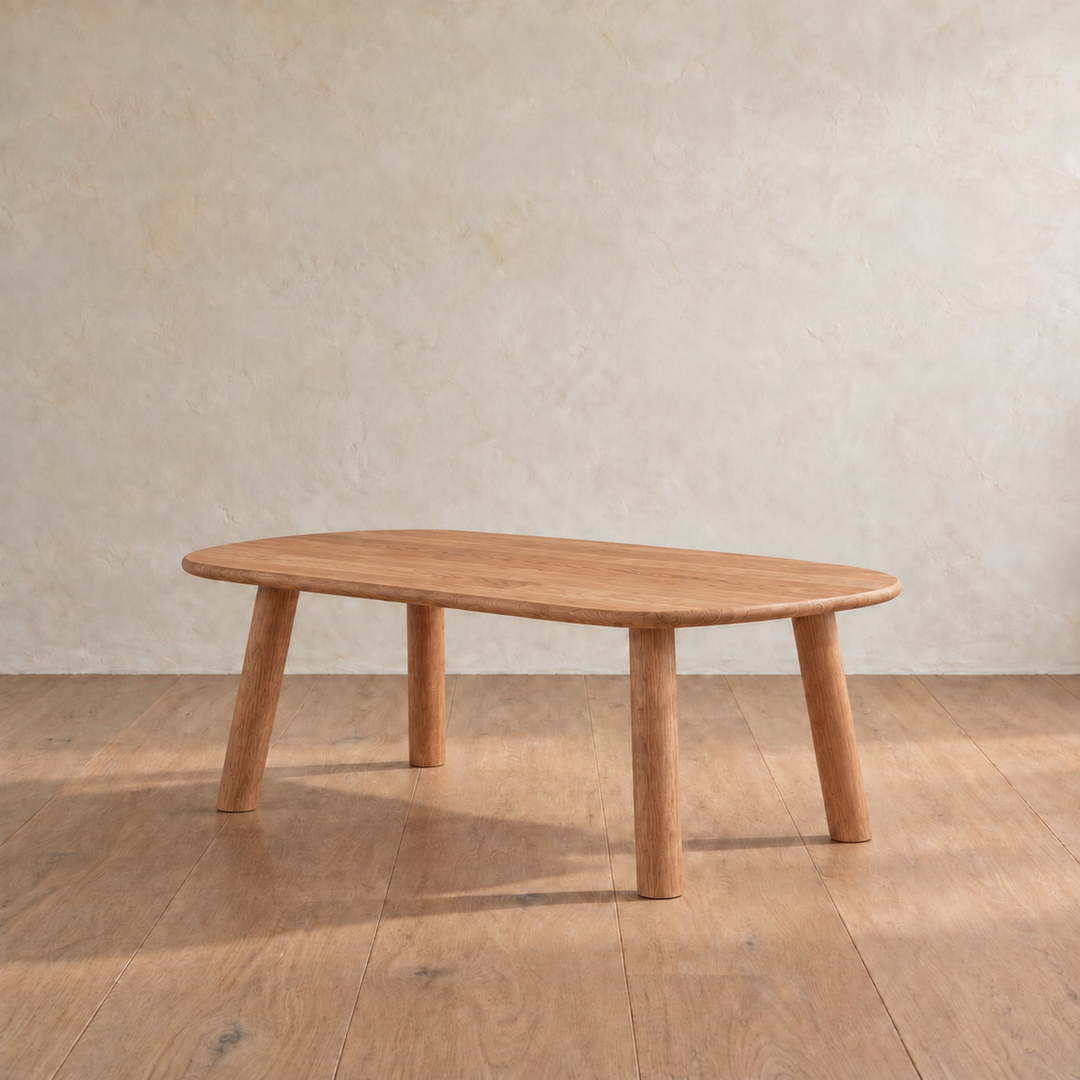 The minimalist coffee table in red oak from the other side, with its four round legs splayed out slightly.