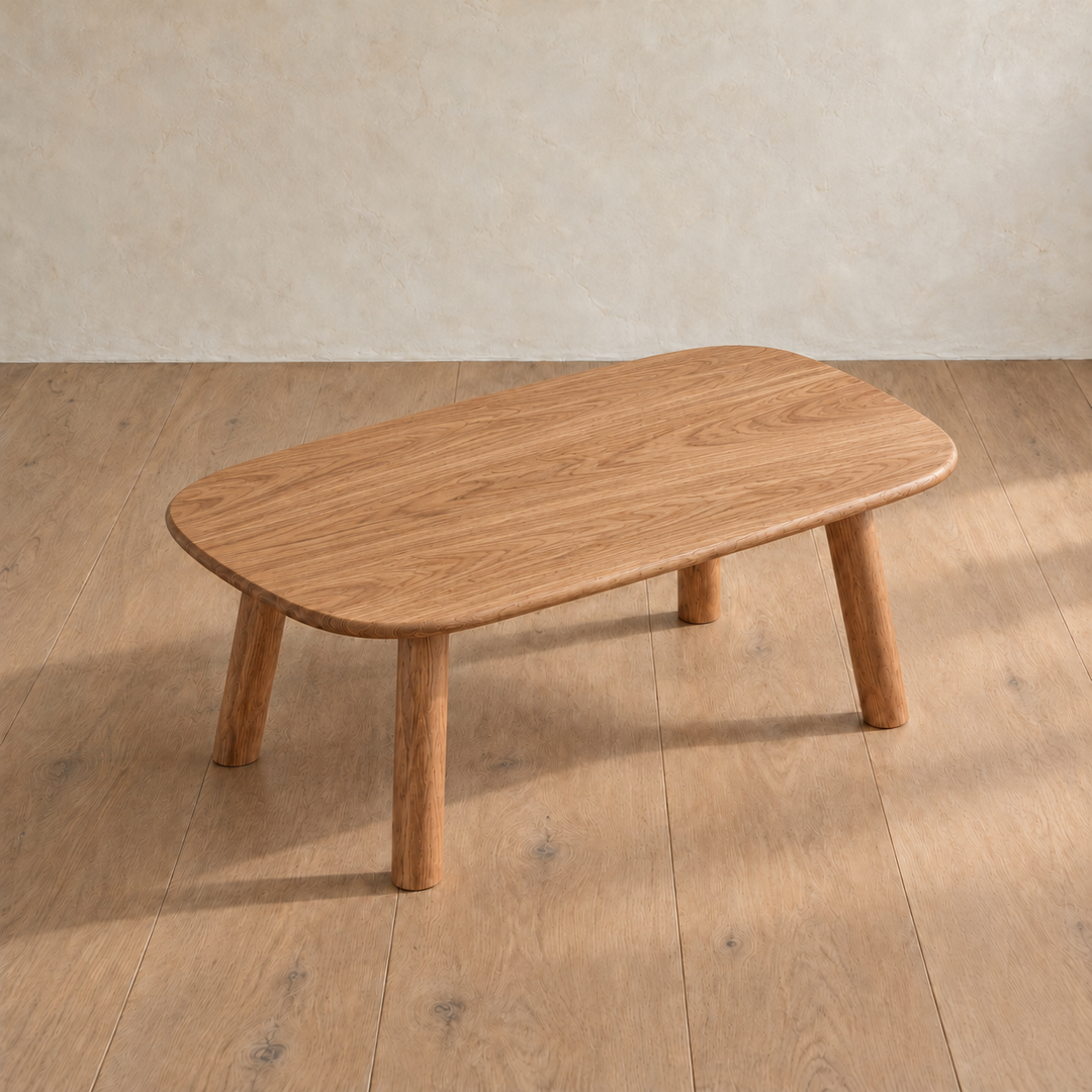 The minimalist coffee table in red oak seen from above at an angle, showing the grain across the top and its rounded corners.
