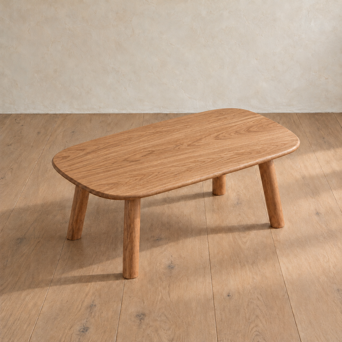 The minimalist coffee table in red oak seen from above at an angle, showing the grain across the top and its rounded corners.