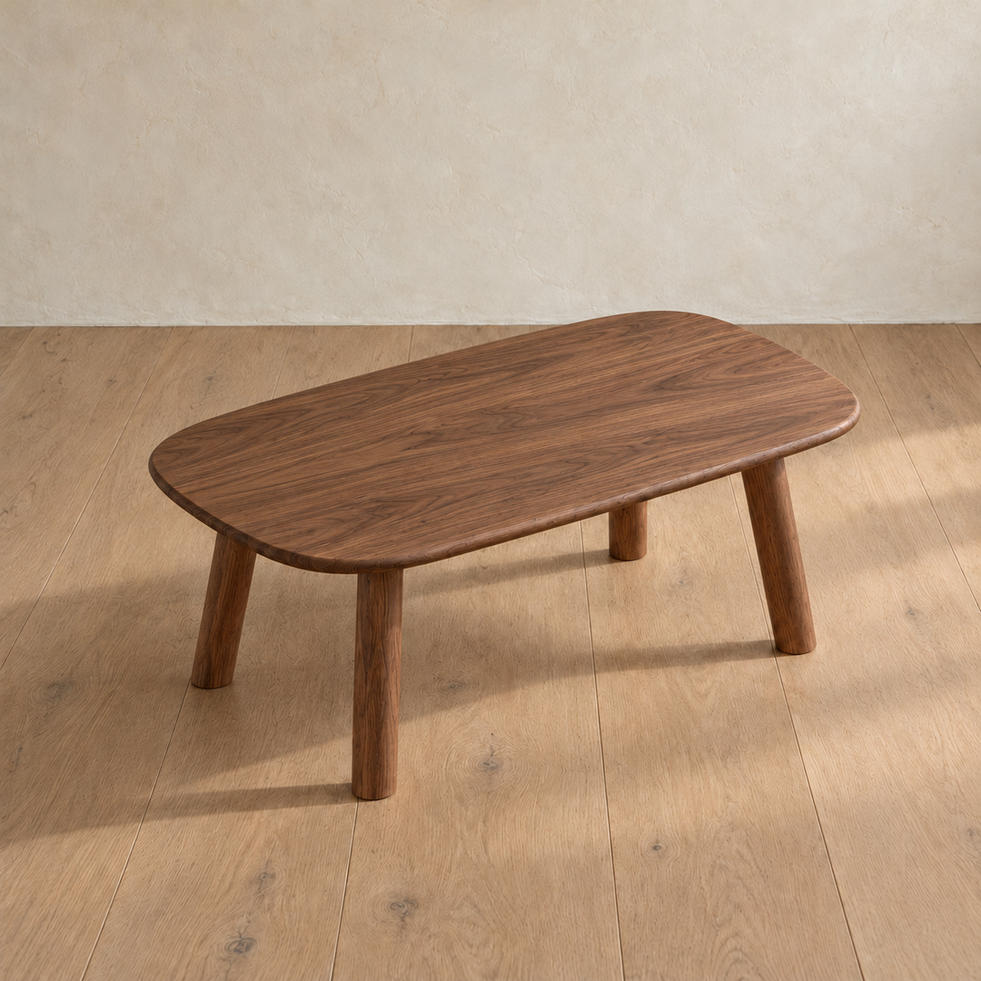 The minimalist coffee table in walnut seen from above at an angle, showing the grain across the top and its rounded corners.
