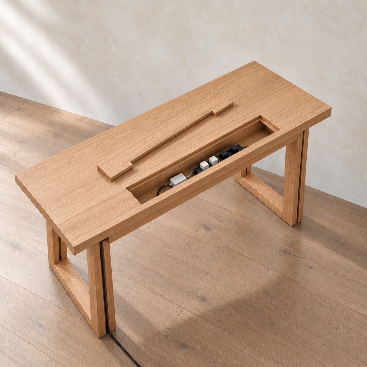 The minimalist office desk in white oak from above, with the cable box lid lifted out to show a power bar and chargers inside.