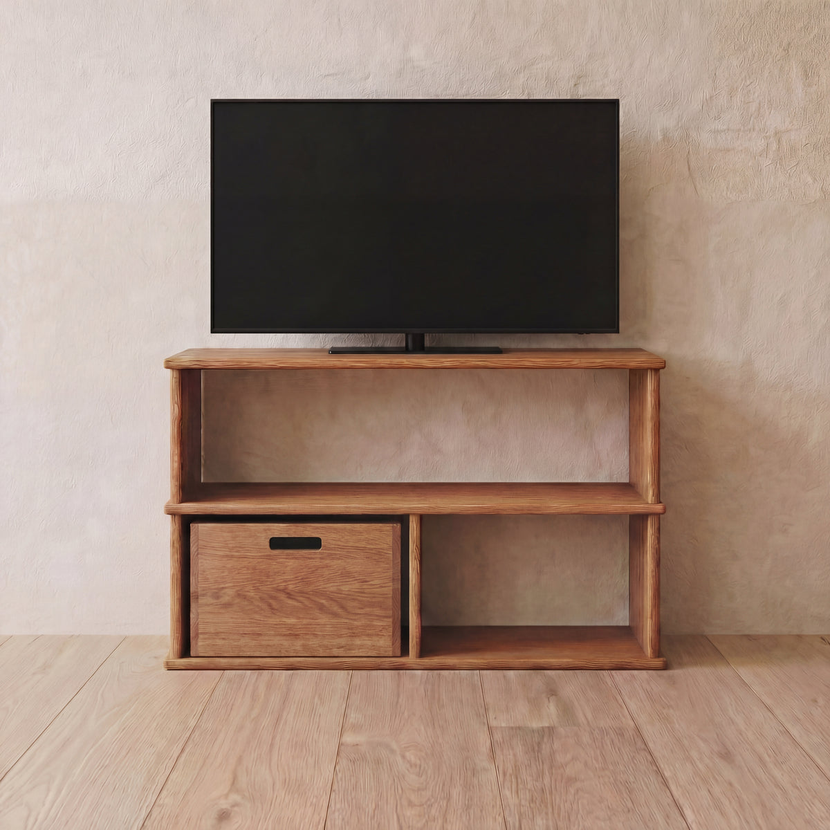 A flat-screen TV on the 40 inch bookshelf TV stand in red oak, with open shelves and a storage cube in one opening, against a light wall on a wooden floor.