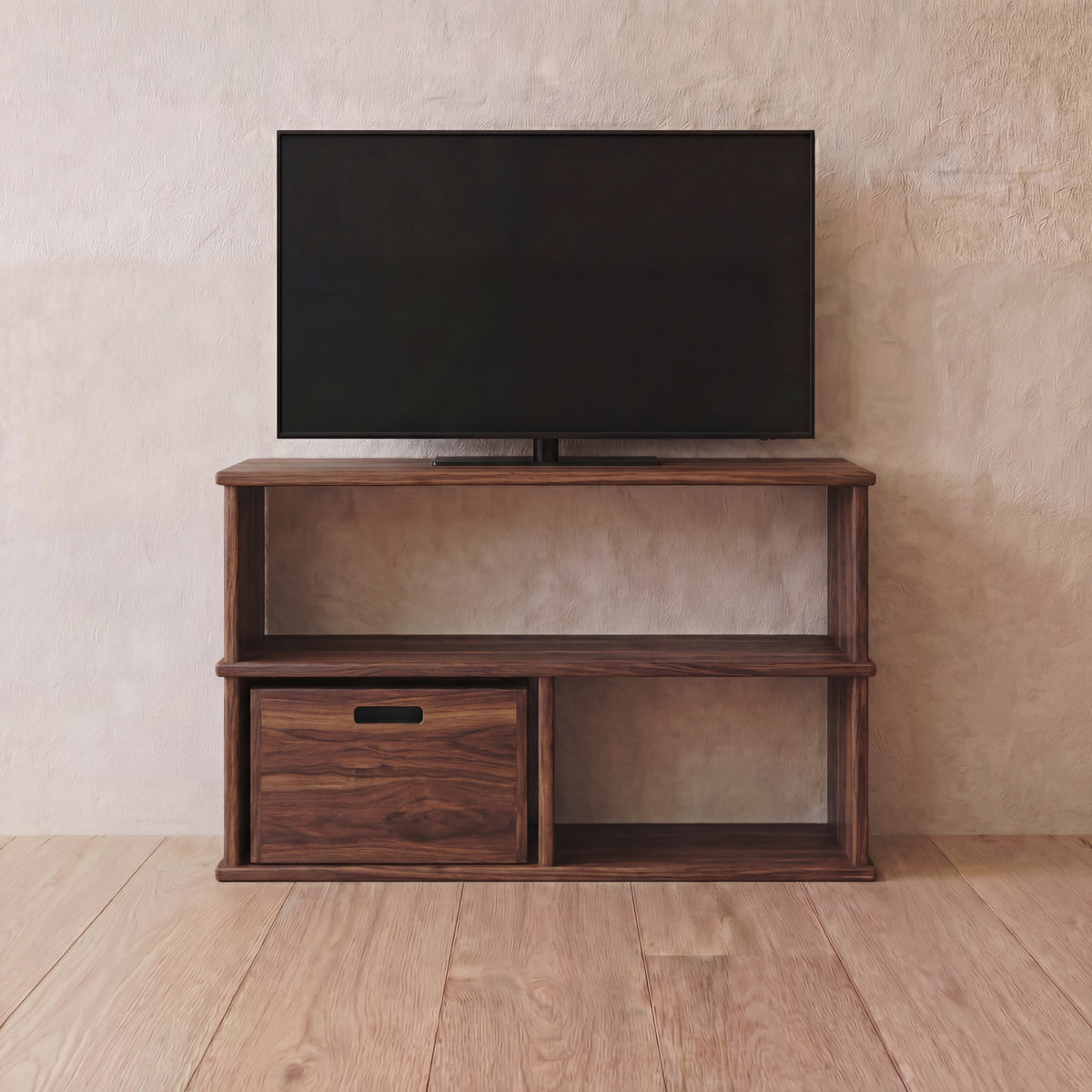 A flat-screen TV on the 40 inch bookshelf TV stand in walnut, with open shelves and a storage cube in the lower left opening, against a light textured wall on a wooden floor.