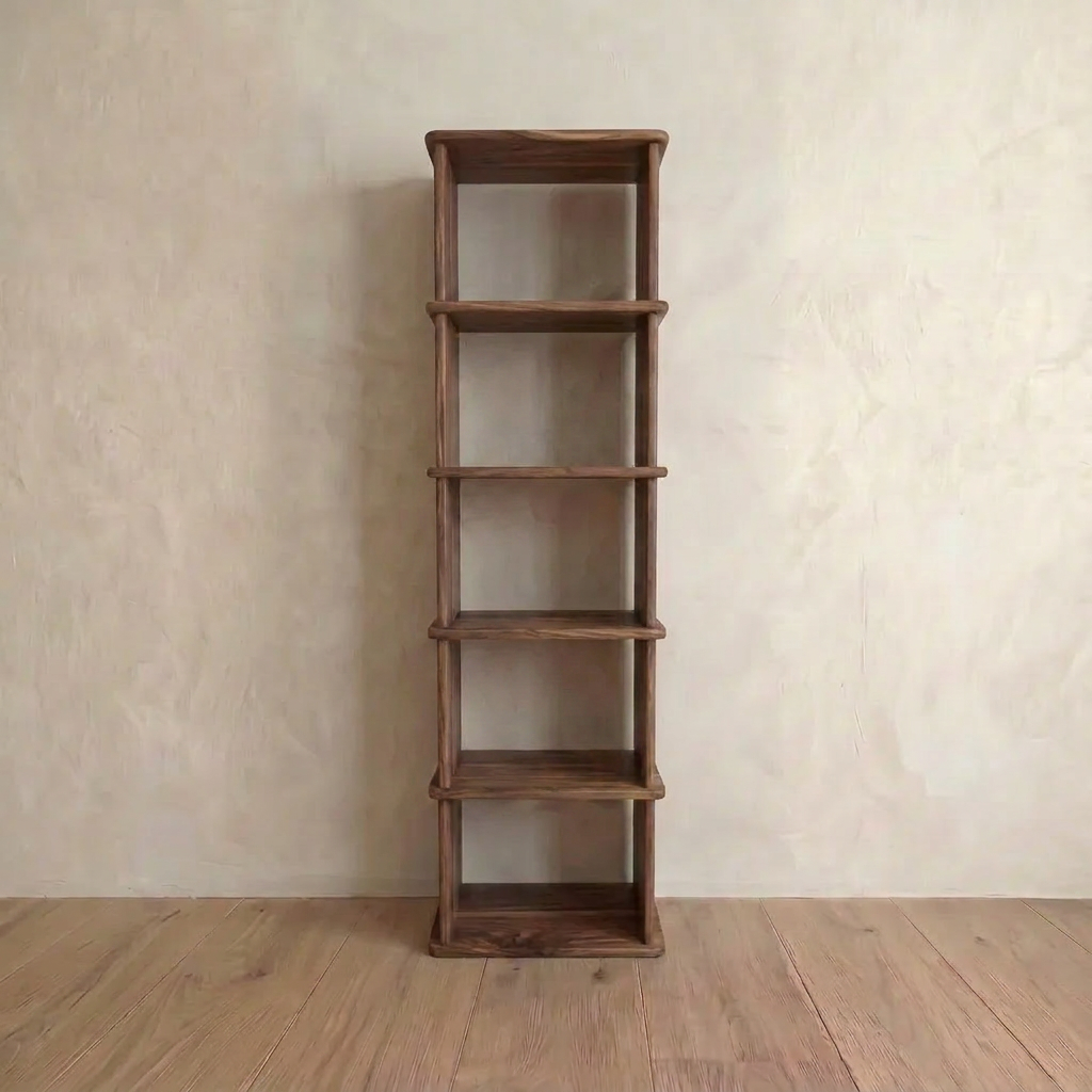 A Narrow bookshelf in walnut with five empty shelves stands against a plain, light-colored wall on a wooden floor.