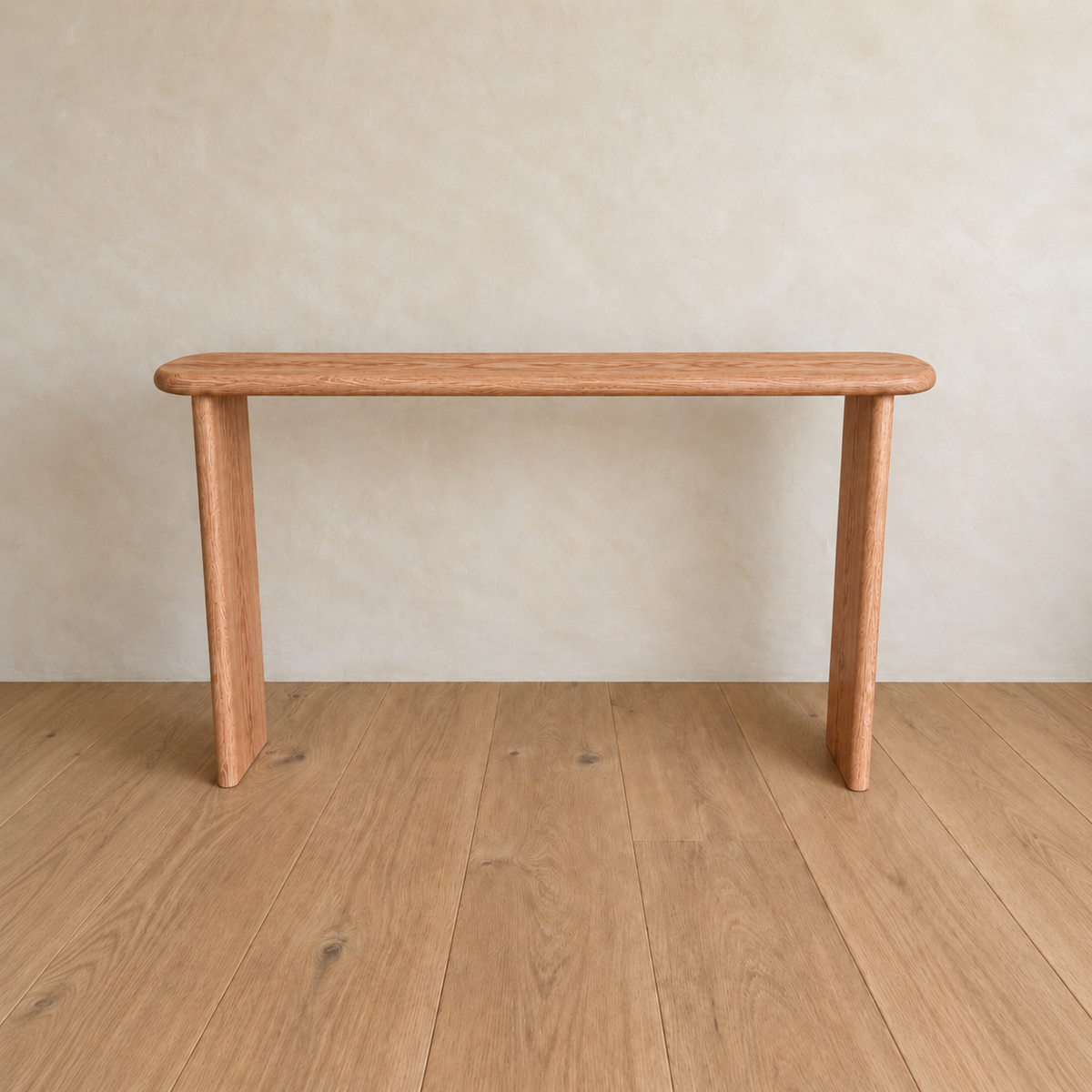 A minimalist Narrow console table in red oak, handmade in Vancouver with three legs, is placed on a wooden floor against a light beige wall.