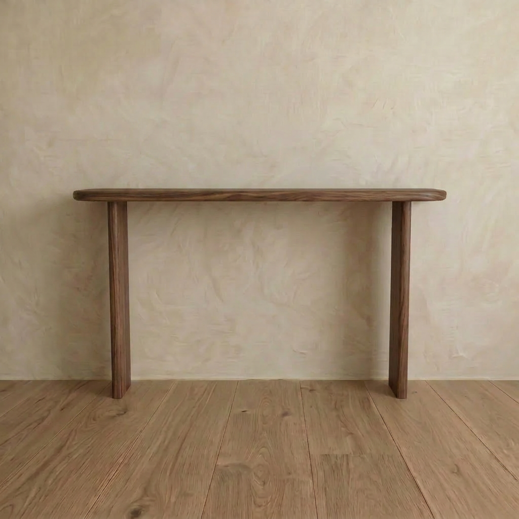 The Narrow console table in walnut features a minimalist two leg design, highlighting clean lines and natural wood grain. Handmade in Vancouver, it stands out against light beige walls and matching wooden floors.
