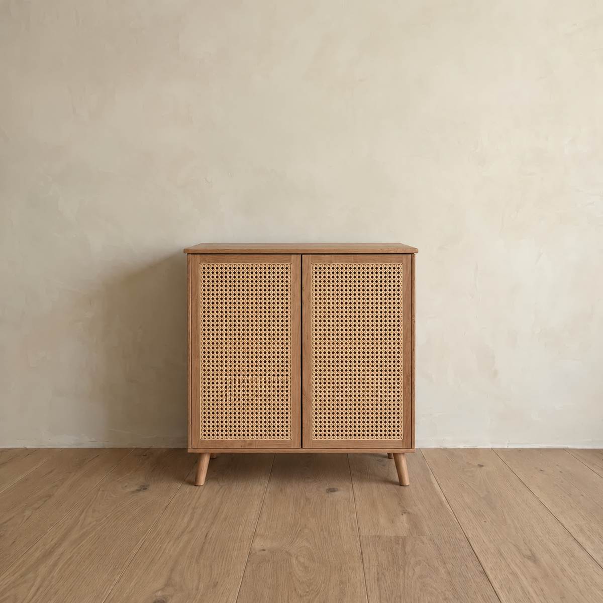 Front view of the rattan cabinet in red oak, standing on its own against a plain plaster wall.