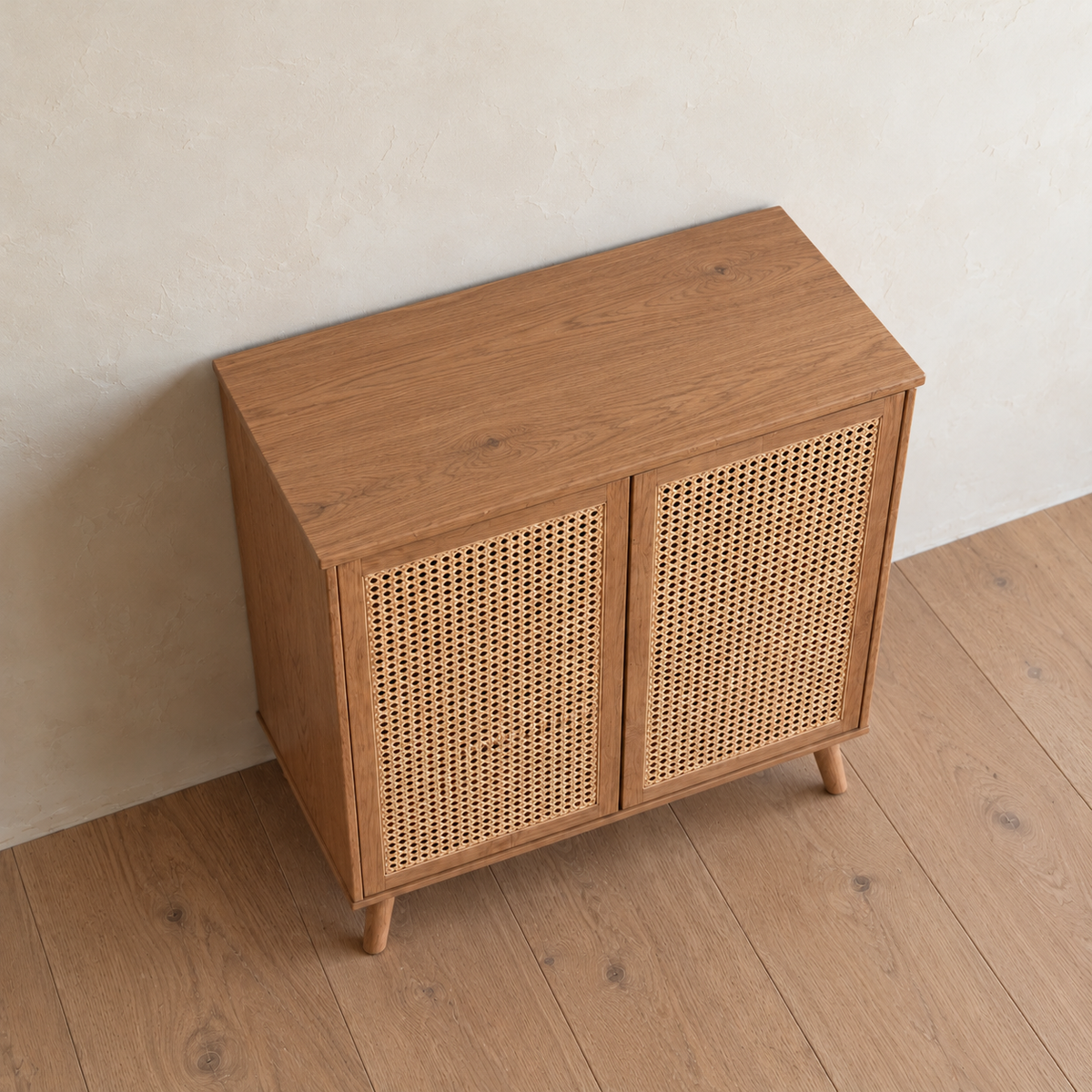 The rattan cabinet in red oak seen from above at an angle, showing the solid red oak top and the woven cane in the doors.