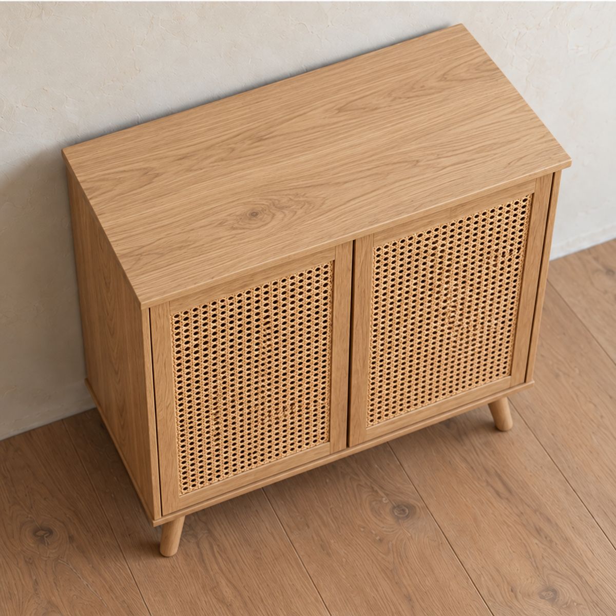 The rattan cabinet in white oak seen from above at an angle, showing the solid white oak top and the woven cane in the doors.