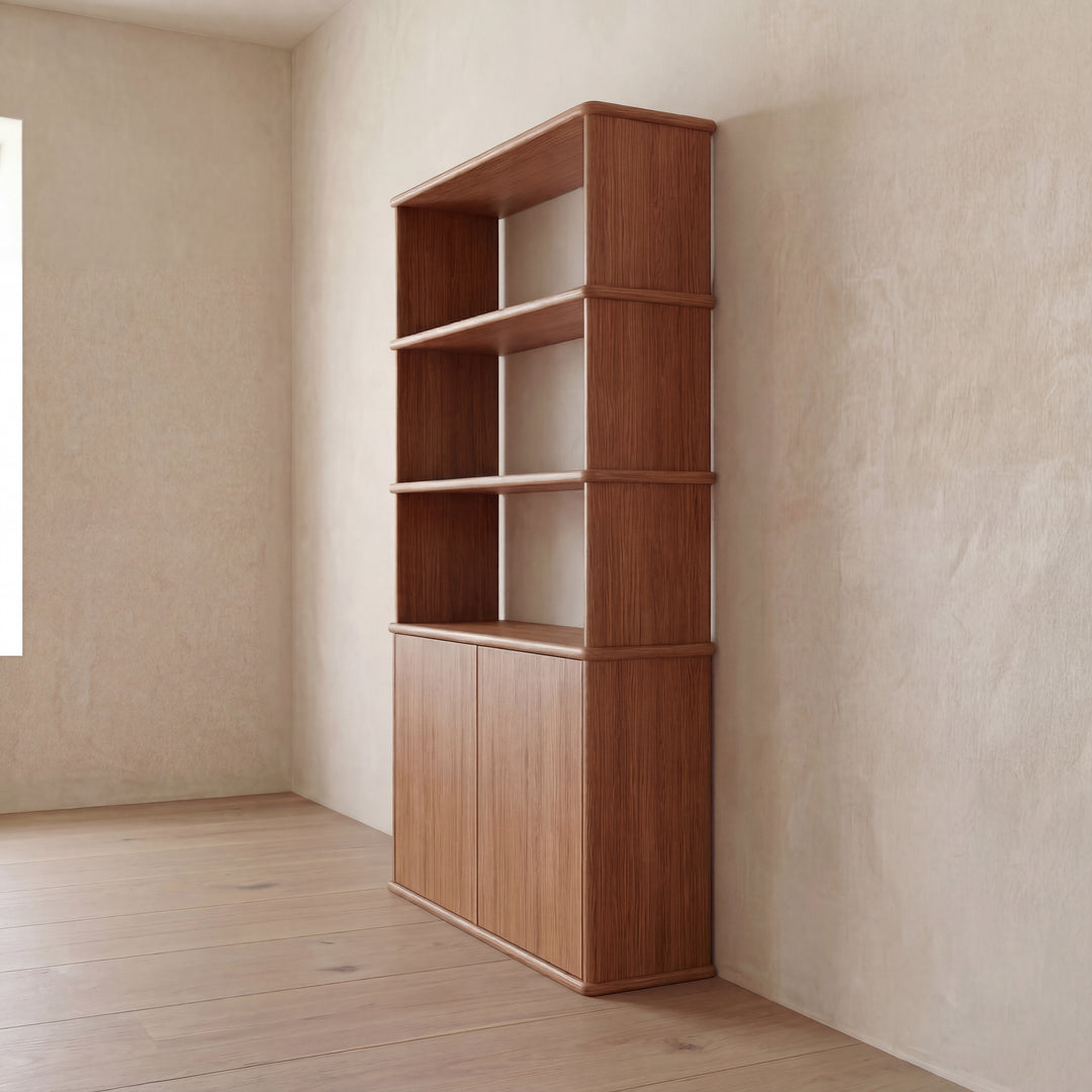 The Cabinet bookshelf in red oak, featuring three open shelves and a closed cabinet with push-to-open doors, stands against a beige textured wall in a minimalistic, sunlit Vancouver room with wooden floors.