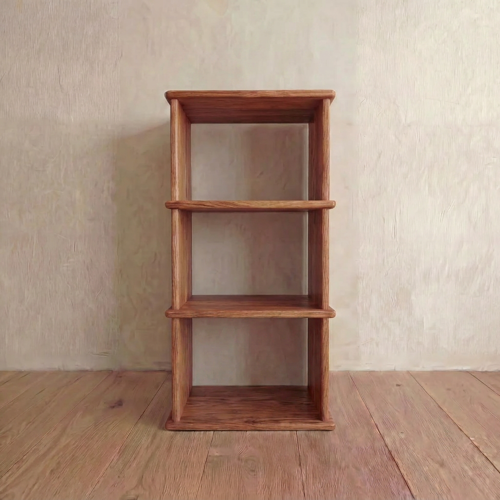 A Small Bookshelf in Red Oak with three handmade tiers stands empty against a textured beige wall on a wooden floor.