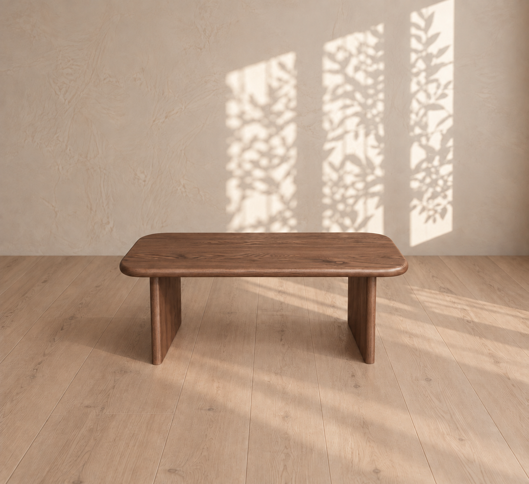 A 40 inch coffee table in walnut sits on a light wood floor with tree branch shadows cast on the beige wall behind it.