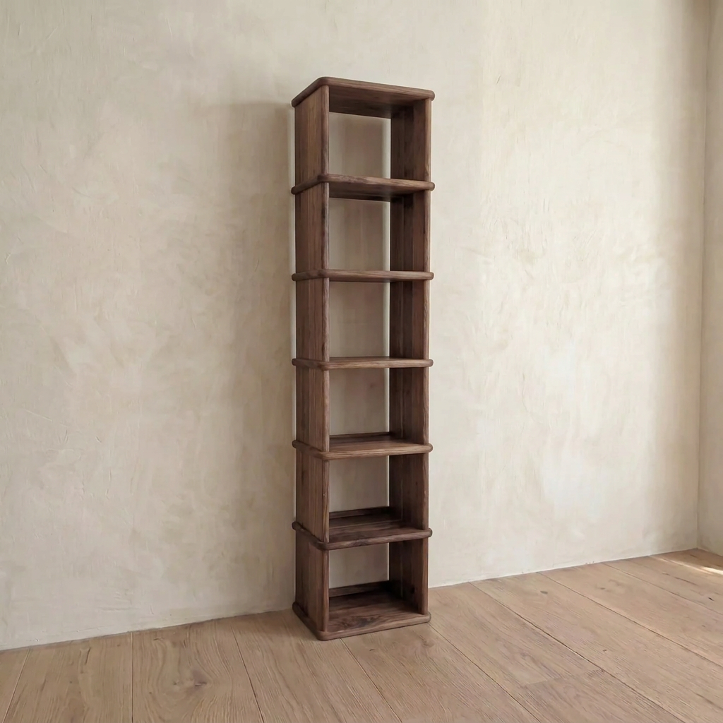 A Tall narrow bookcase in walnut with six shelves stands against a light wall on a wooden floor in a minimalist Vancouver room.