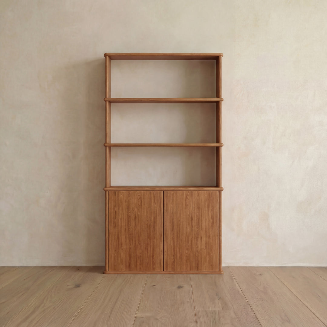 Introducing the Cabinet bookshelf in red oak, featuring three open shelves above and two push-to-open doors below. Set against a light beige wall on a wooden floor, this stylish piece is perfect for adding warmth and functionality to any Vancouver home.
